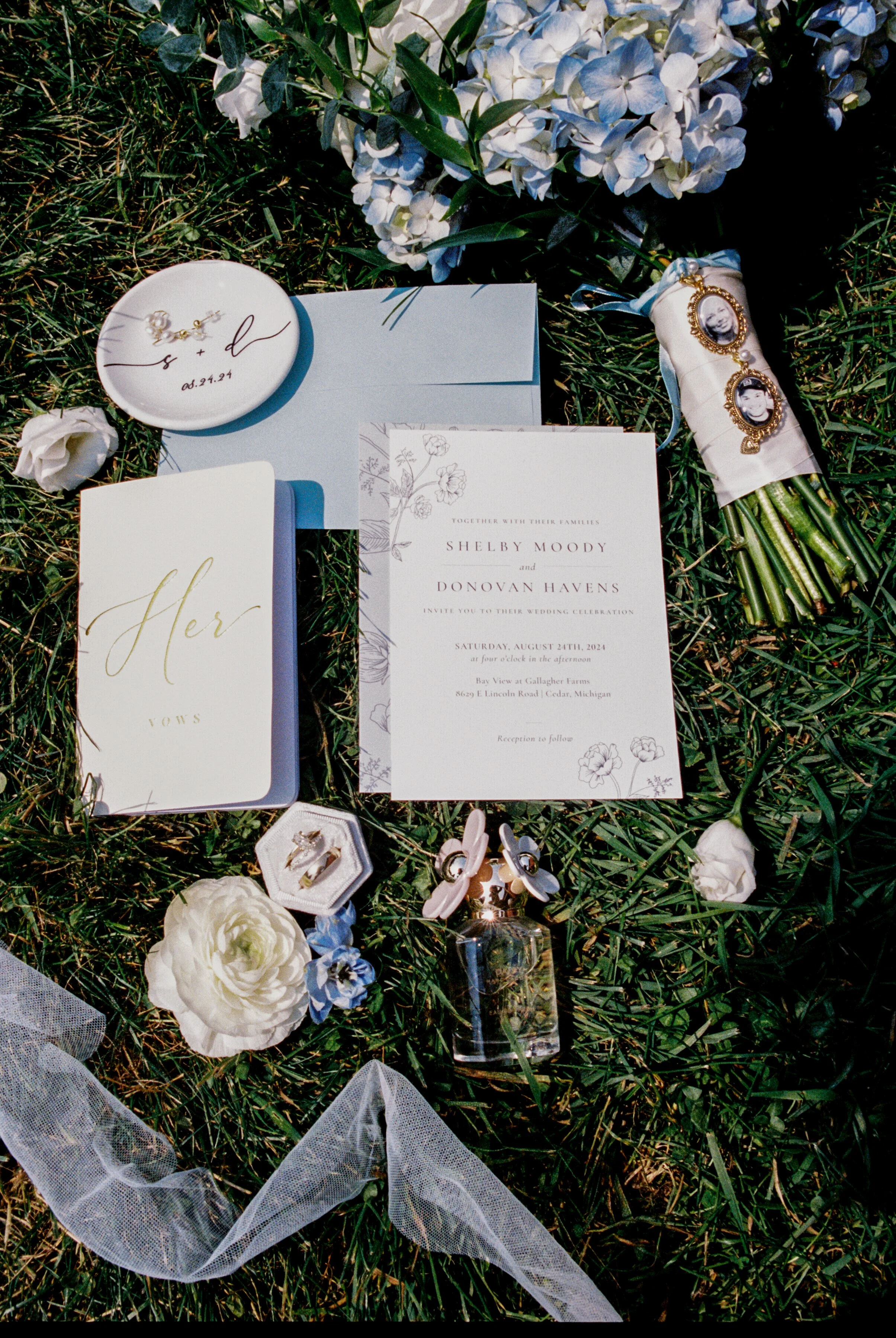 Wedding invitation suite, vow book, rings, bouquet, and heirloom details styled together on the grass at a Northern Michigan vineyard wedding.