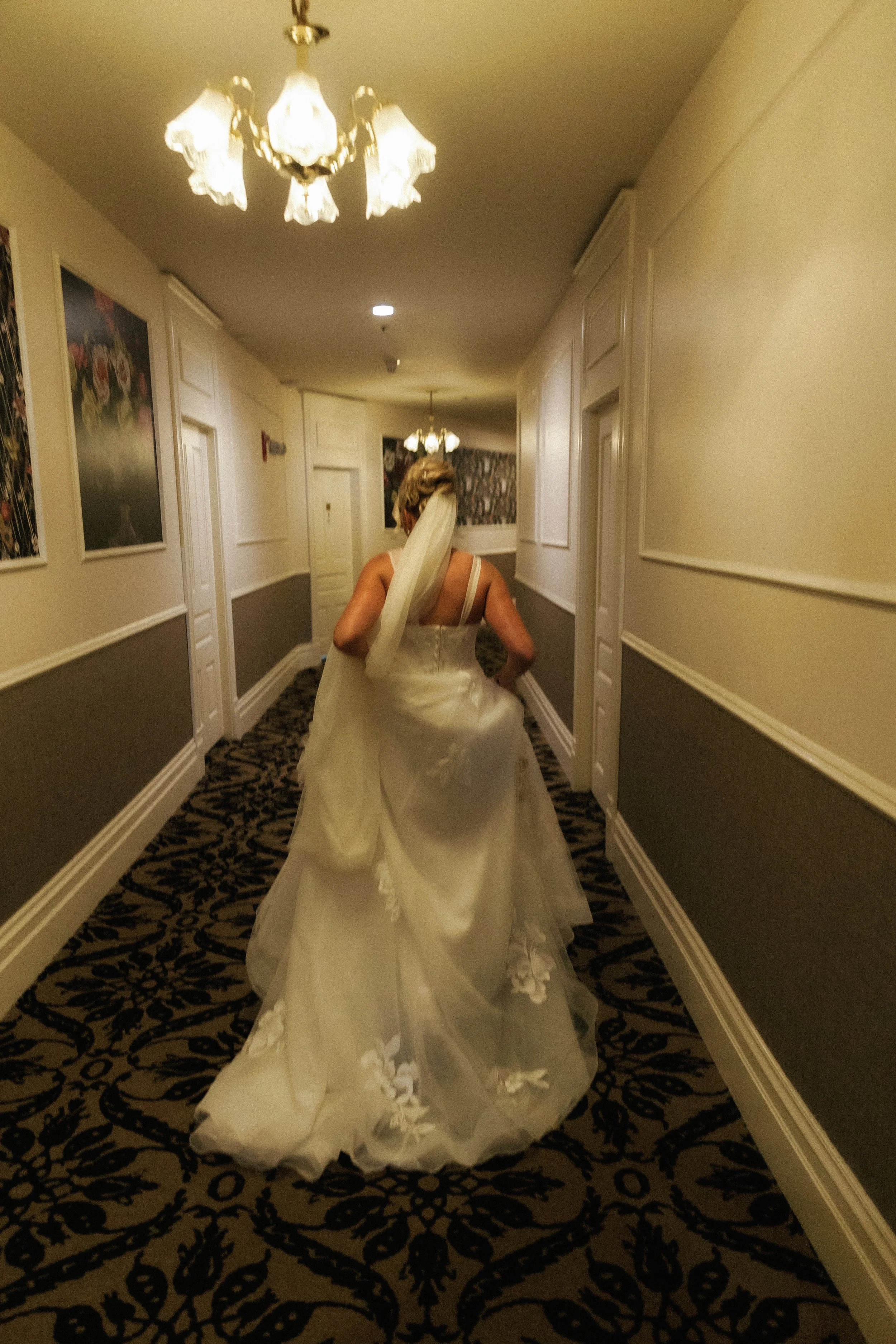 Bride walking through the hotel hallway in her wedding dress before the reception at Stafford's Perry Hotel.