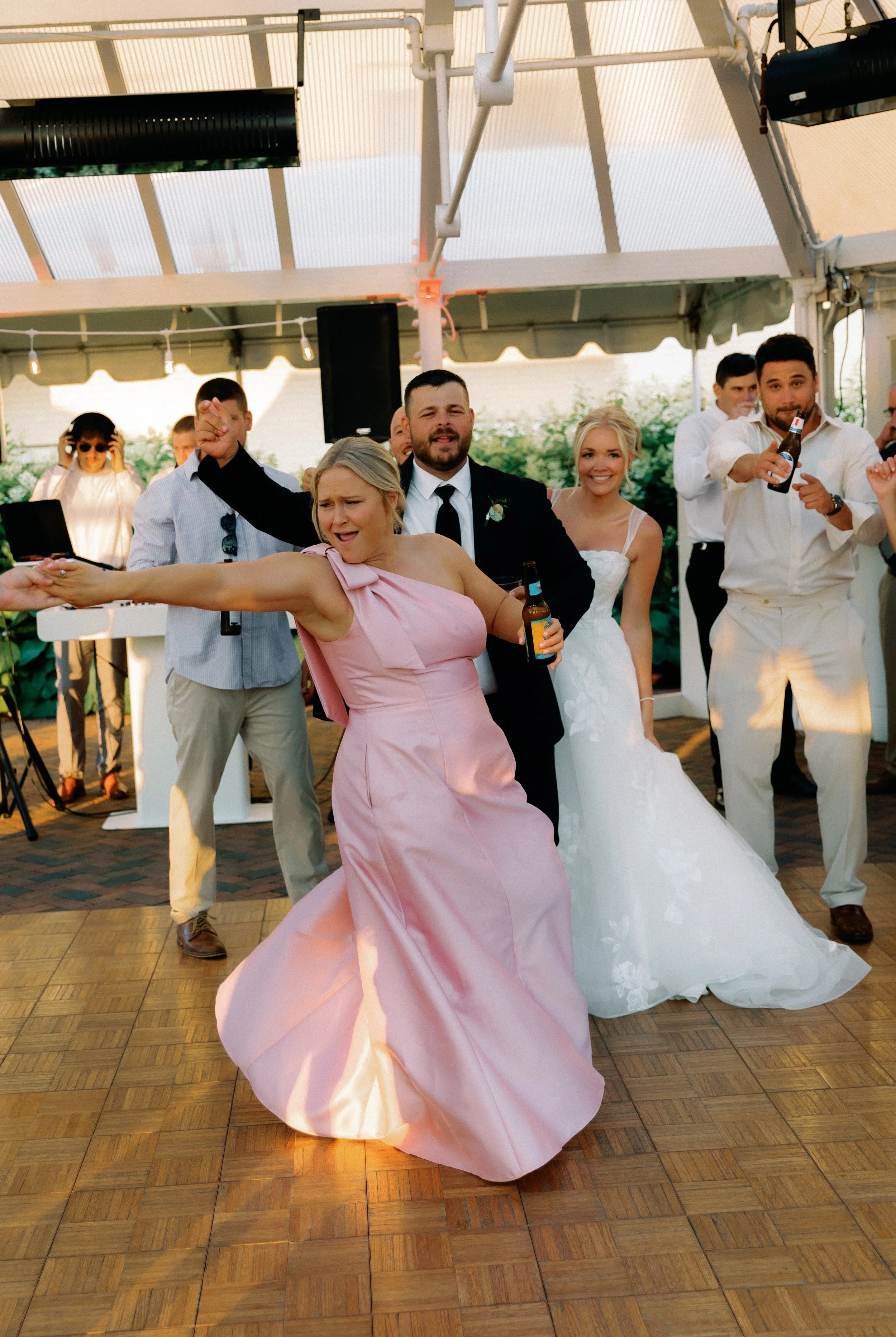 Bridesmaid dancing at the reception while guests cheer and celebrate around her.