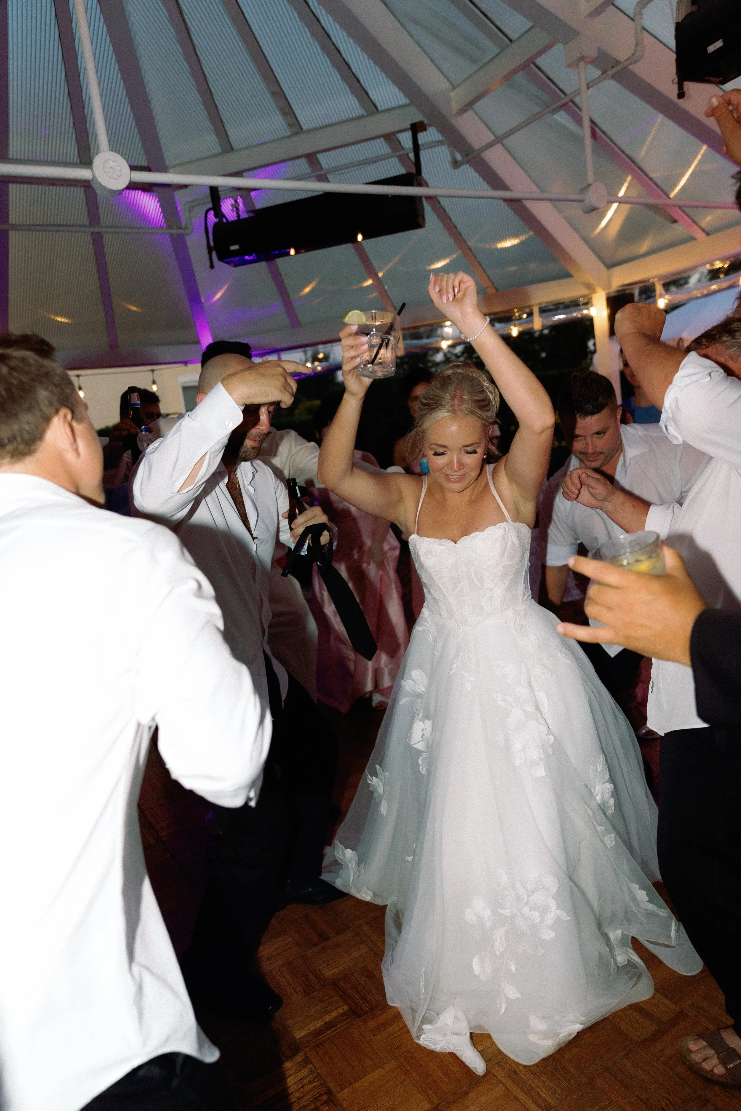 Bride dancing on the reception dance floor surrounded by friends and family.