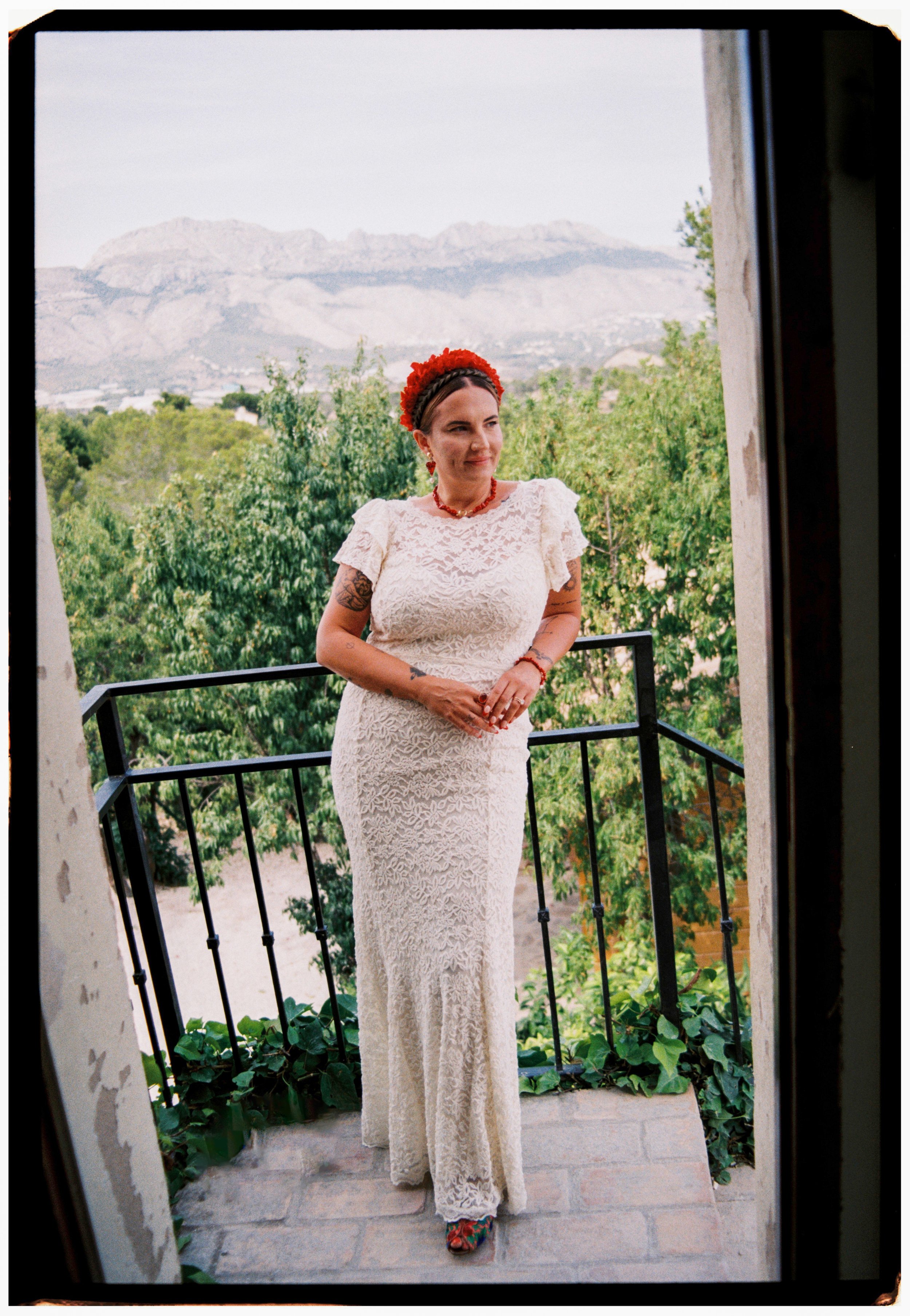 Bride standing on a balcony with mountain views during her Spain wedding.