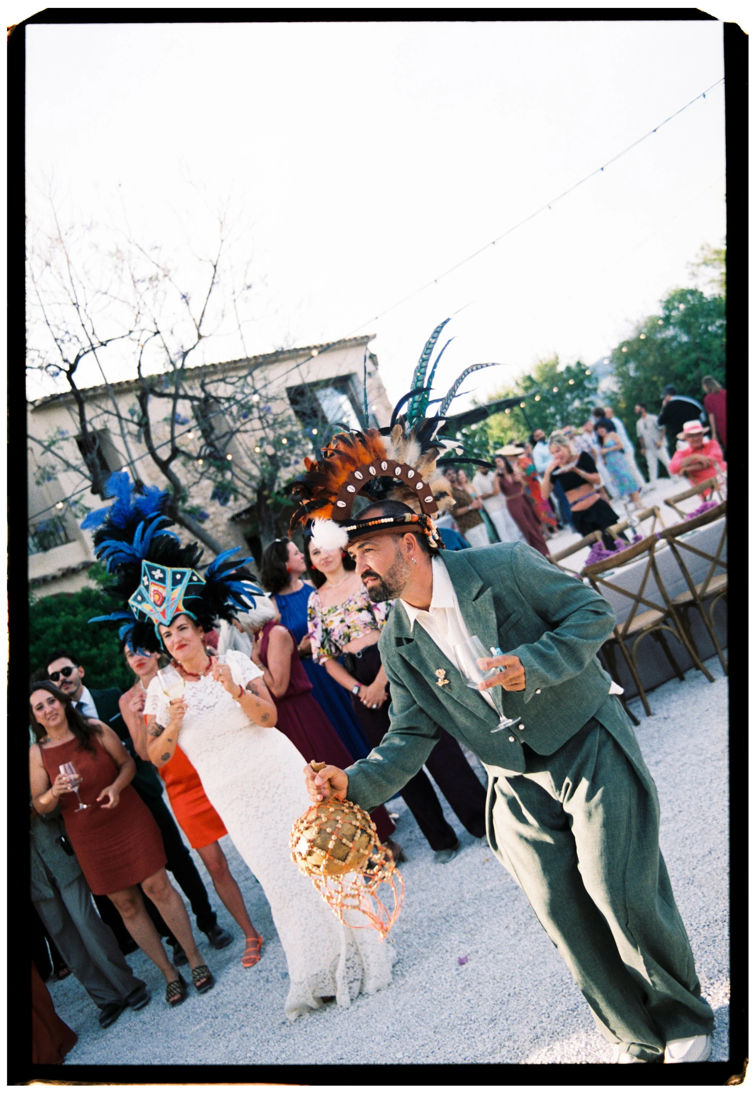 Groom wearing a festive feathered hat while celebrating with guests during a Spain wedding.