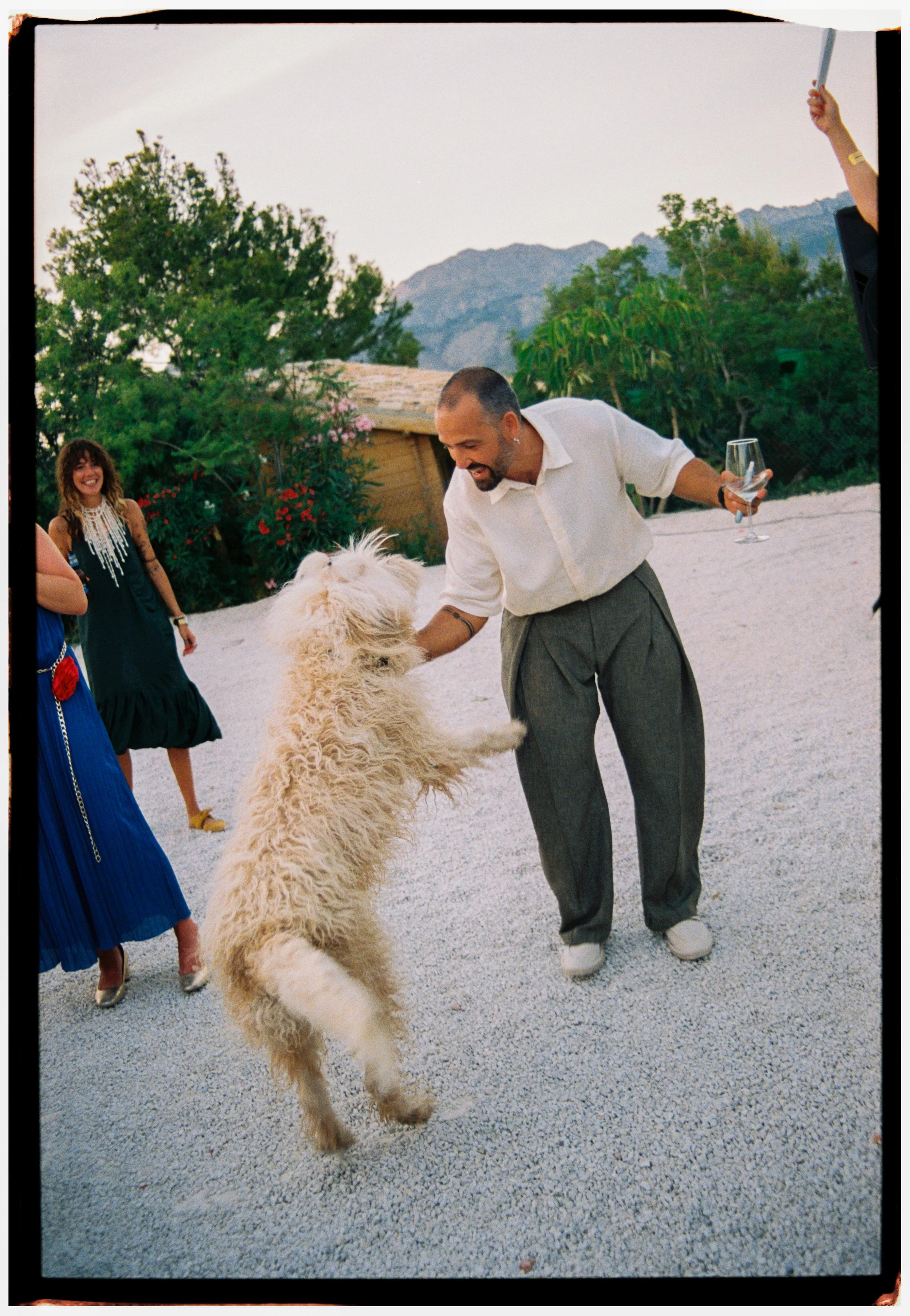 Groom dancing with a fluffy white dog during the wedding reception.