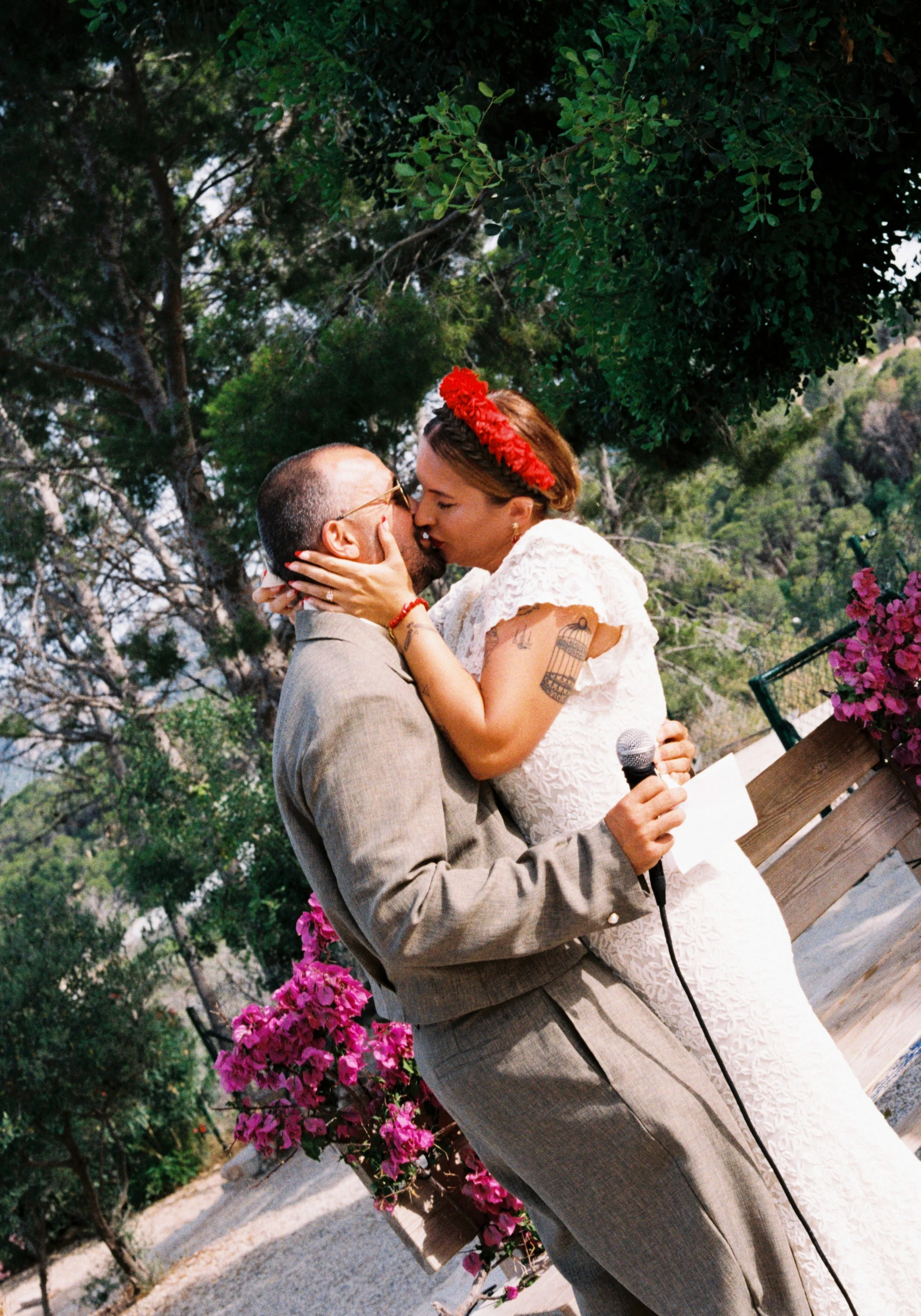 Bride and groom sharing a kiss during their Spain wedding ceremony surrounded by blooming flowers.