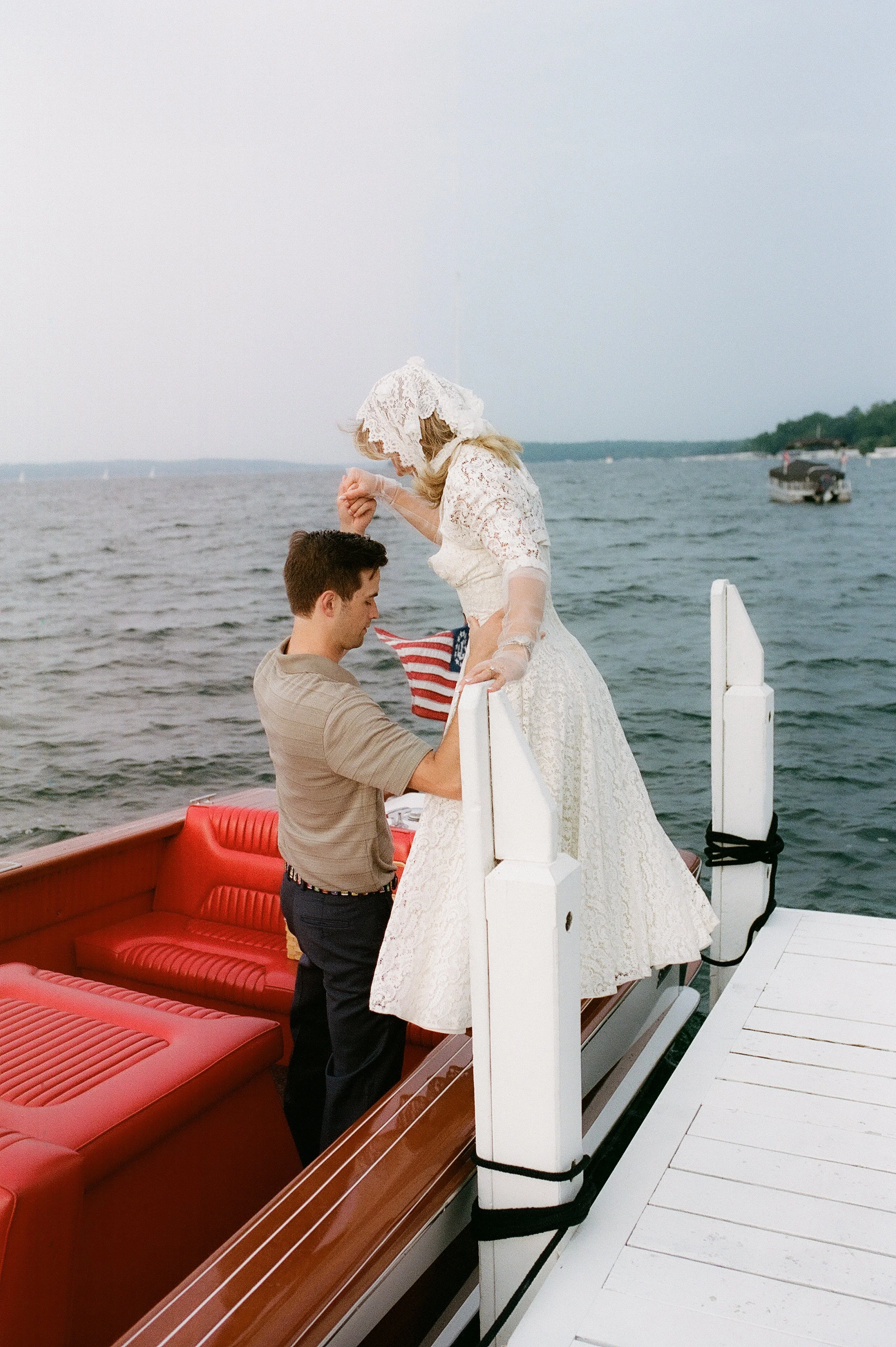 Bride stepping onto a dock while holding her fiancé's hand after their Lake Geneva Engagement boat ride.