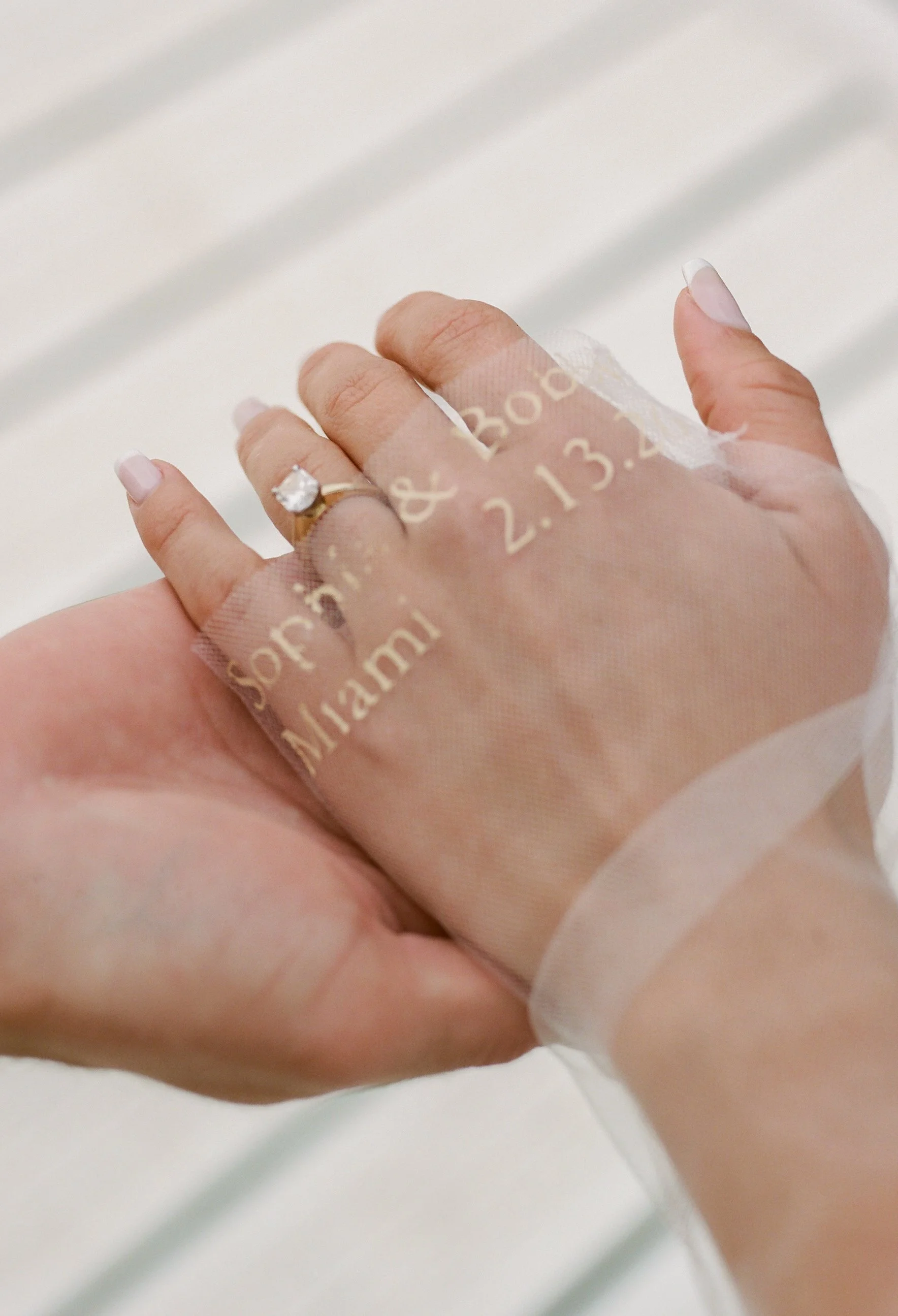 Close-up of the bride's engagement ring with embroidered veil details featuring the couple's names and wedding date during their Lake Geneva Engagement session.