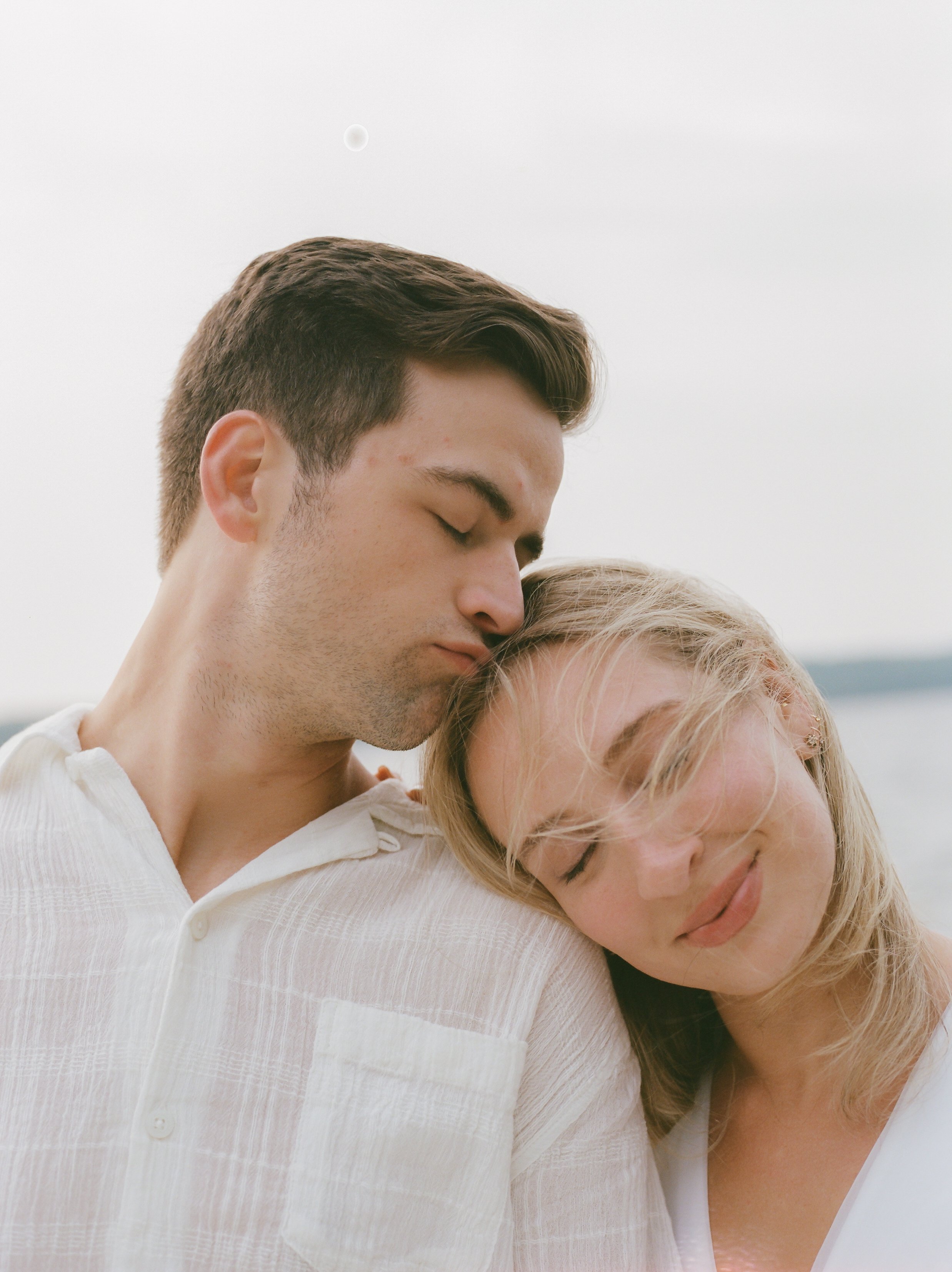 Close-up of an engaged couple sharing a quiet embrace during their Lake Geneva Engagement session by the water.