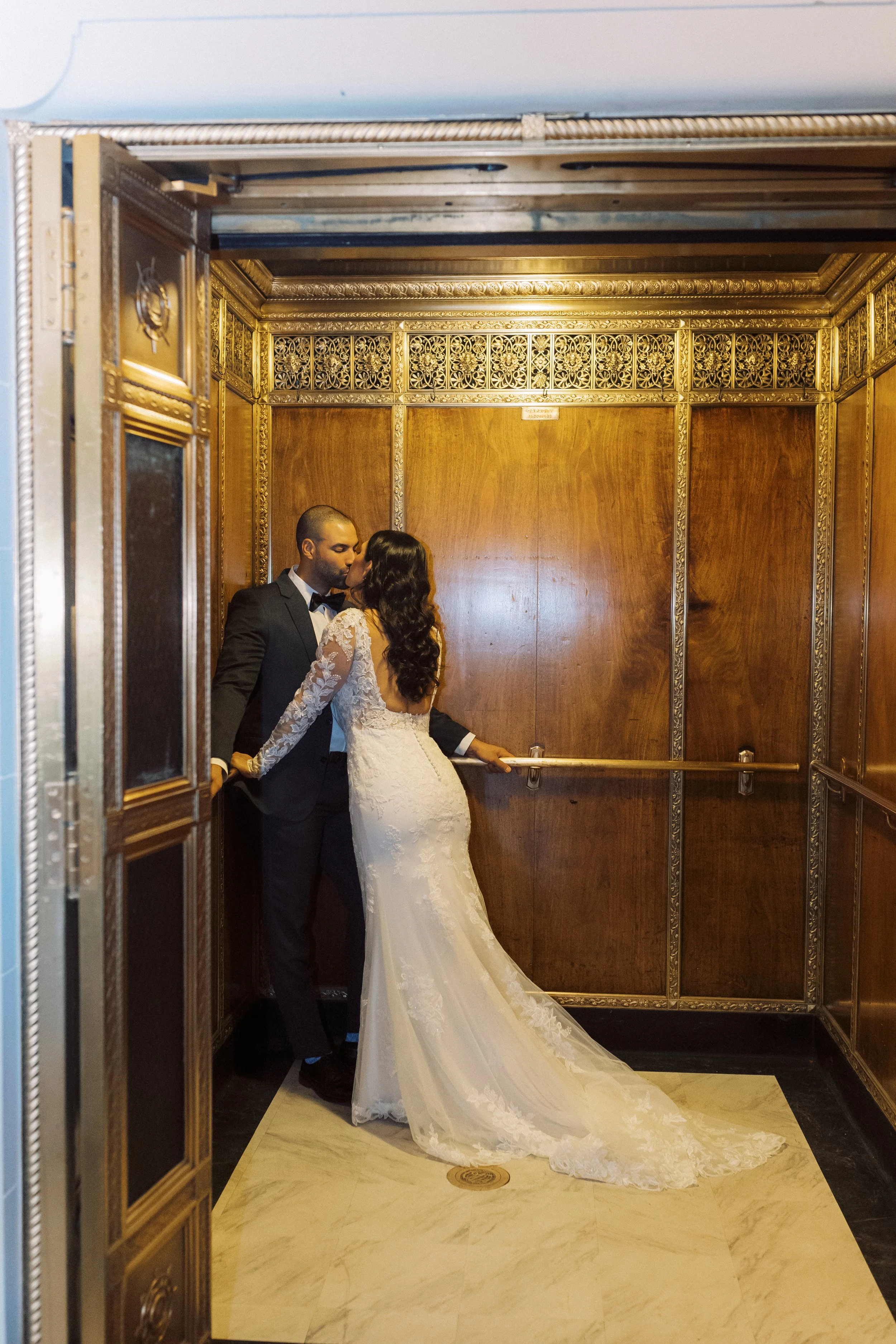 Newlyweds kissing inside a vintage wood-paneled elevator during their downtown Detroit wedding.