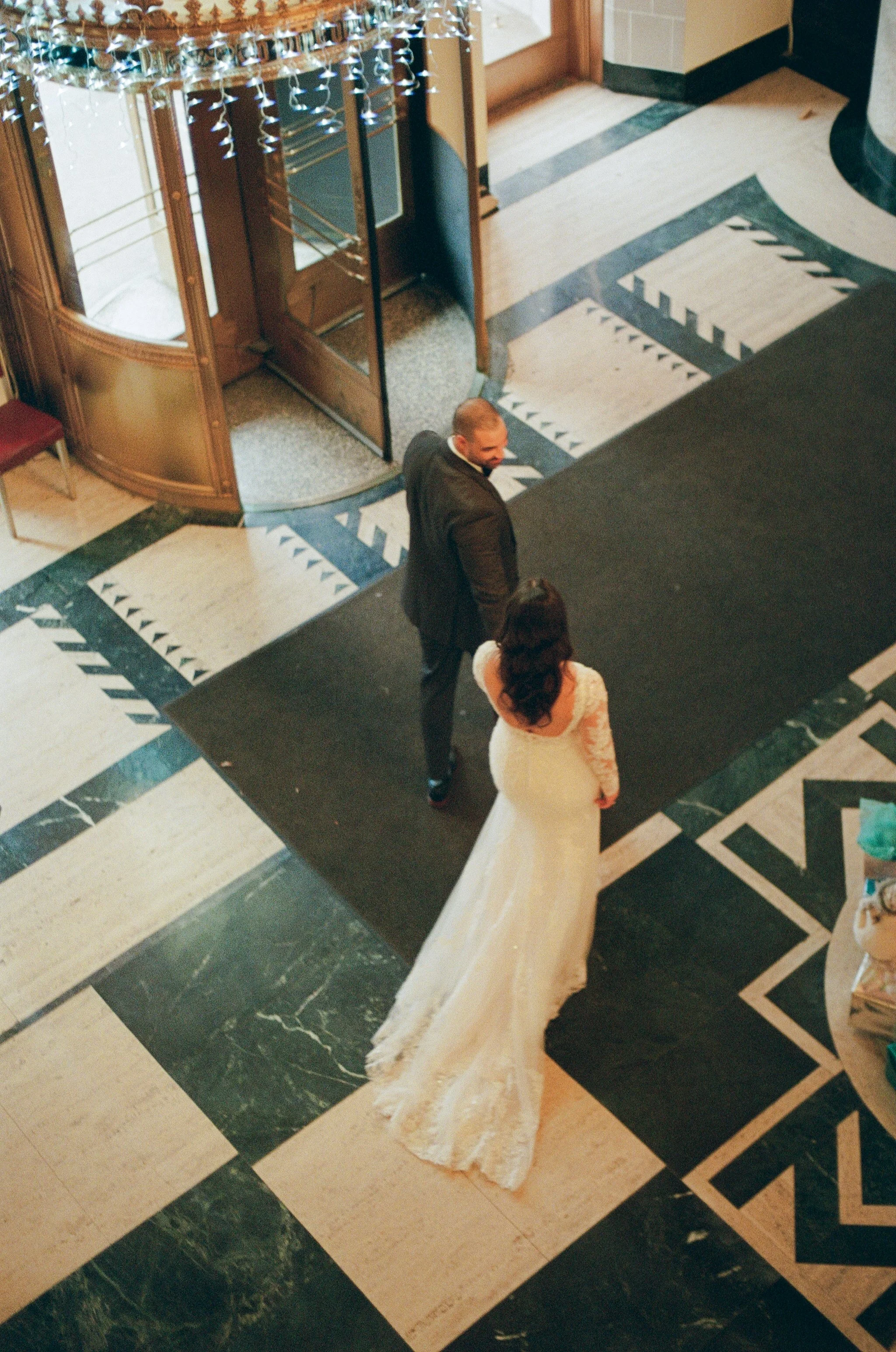 Overhead view of the bride and groom standing together on a geometric marble floor.