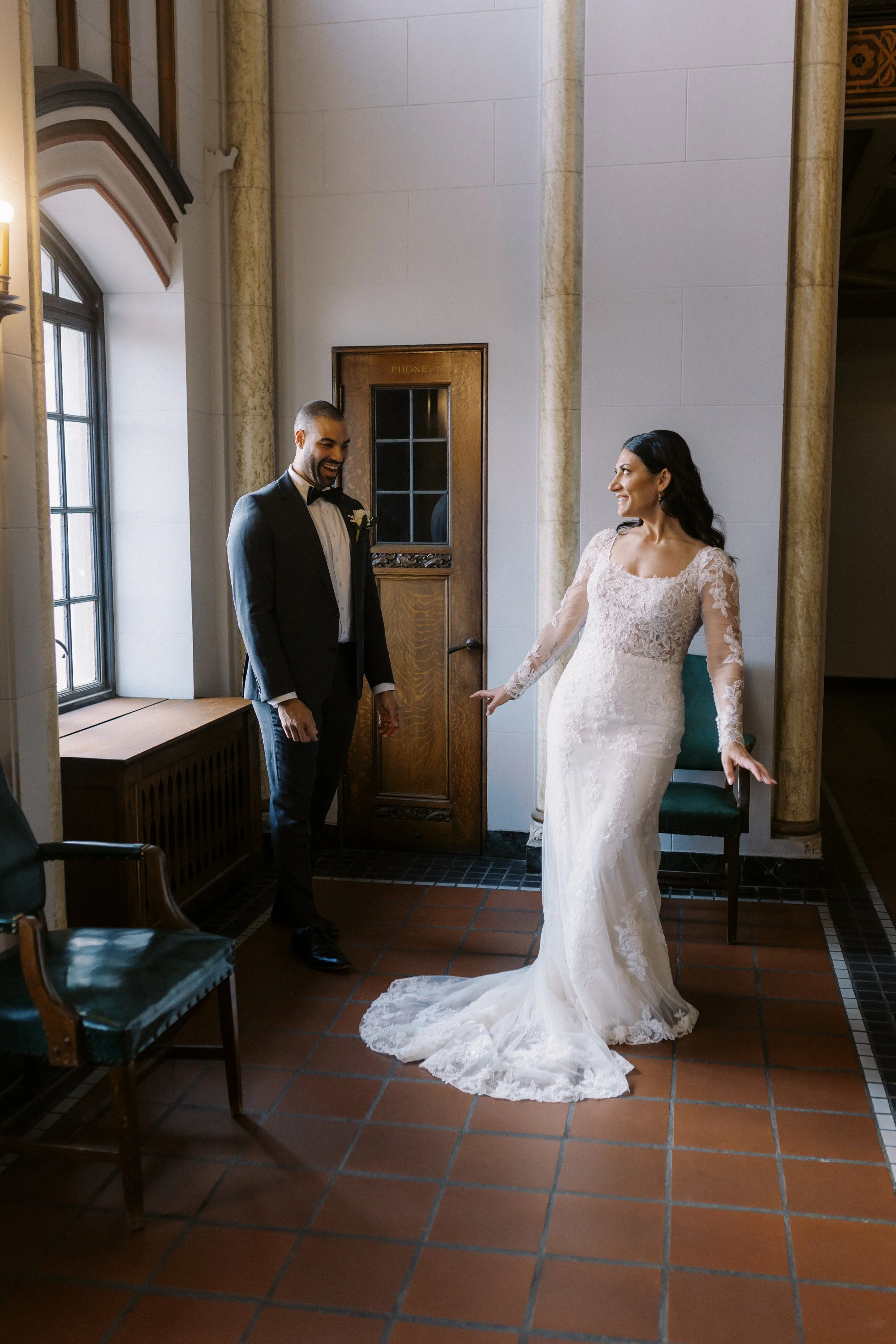 Bride and groom holding hands and sharing a kiss during an intimate indoor wedding portrait.