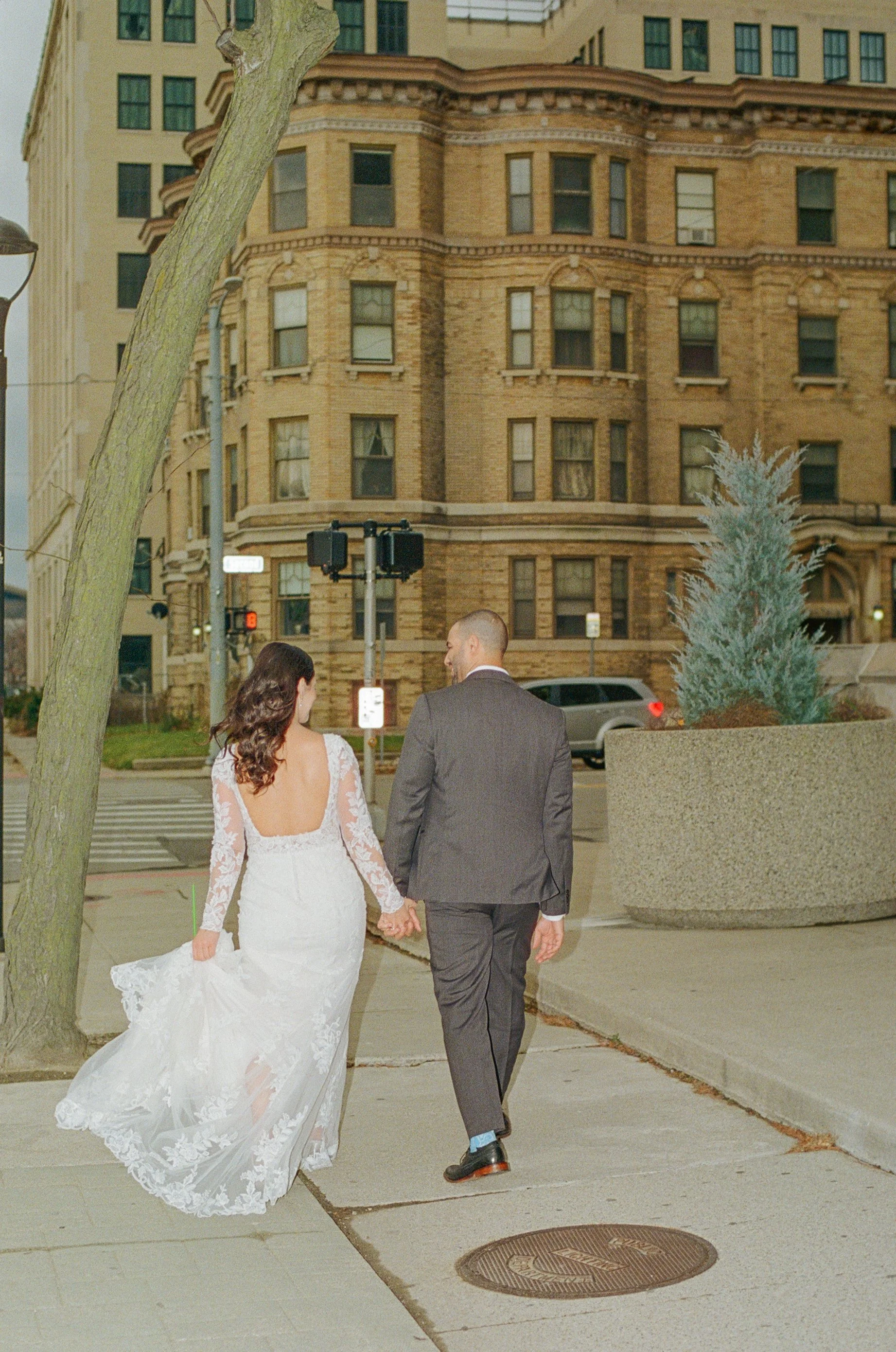 Bride and groom holding hands while walking together through the streets of downtown Detroit.