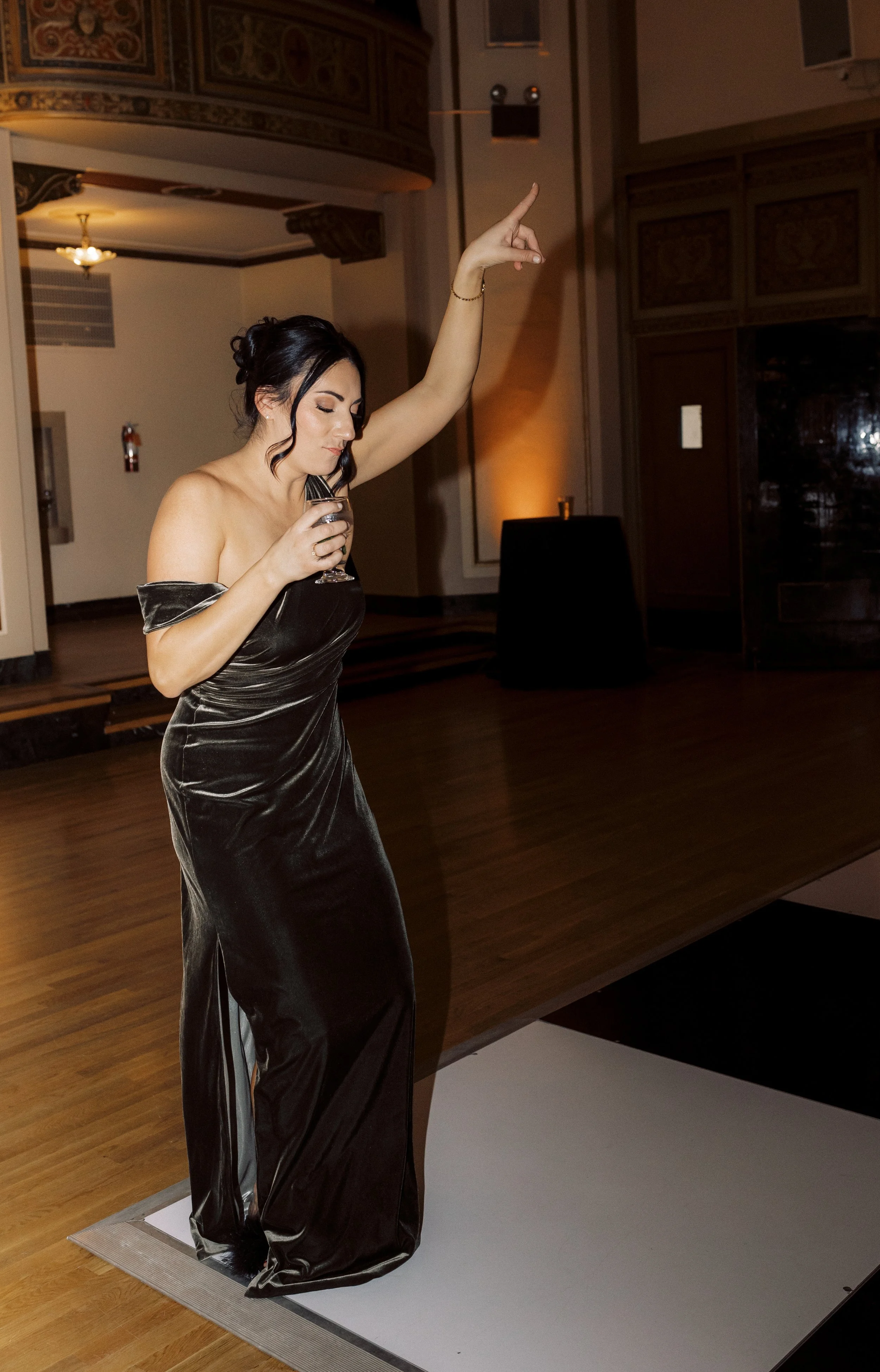 A bridesmaid dances on the dance floor while sipping on a drink