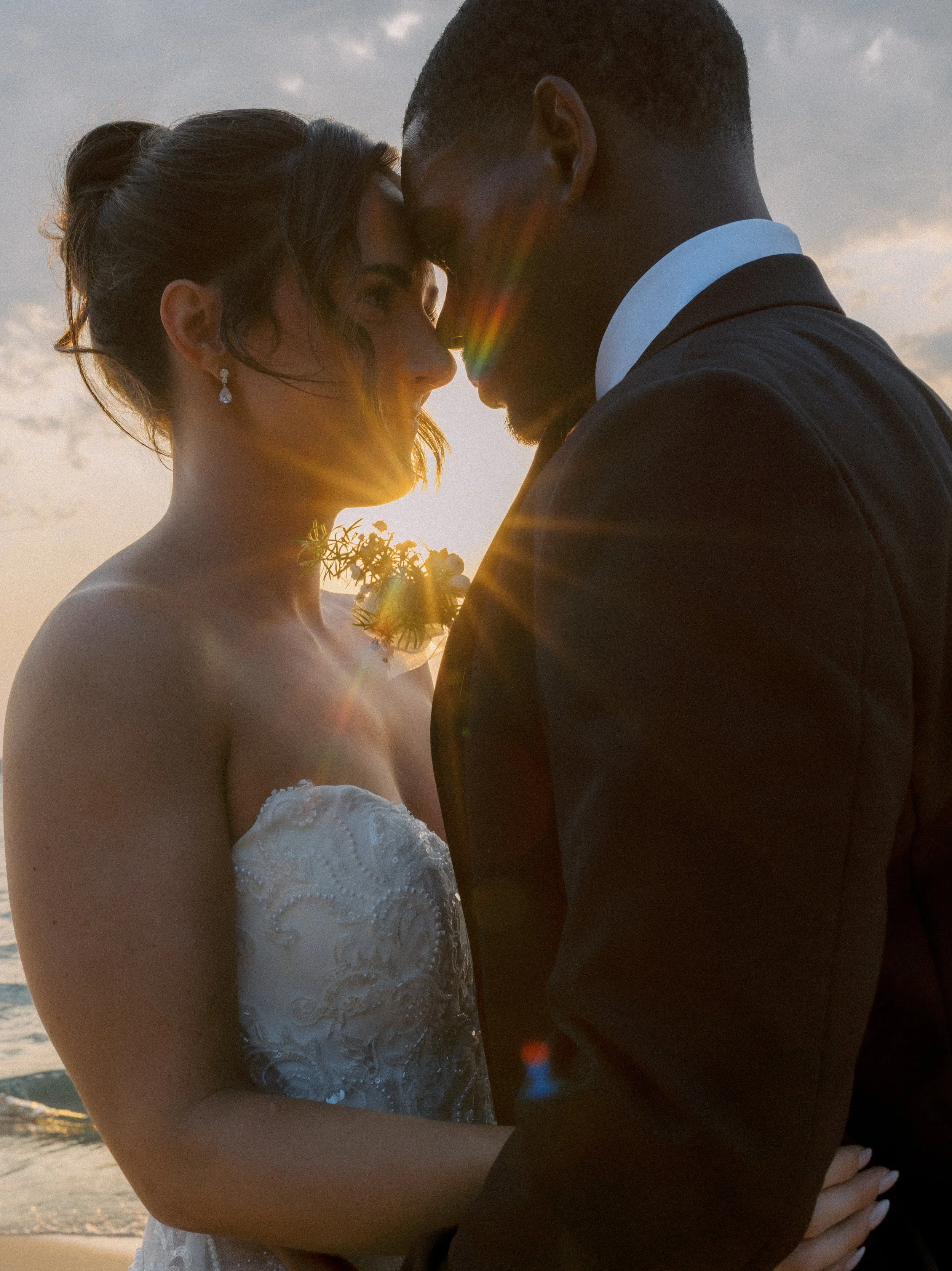 Romantic sunset portrait of the newlyweds embracing by the lake during their Northern Michigan backyard wedding.
