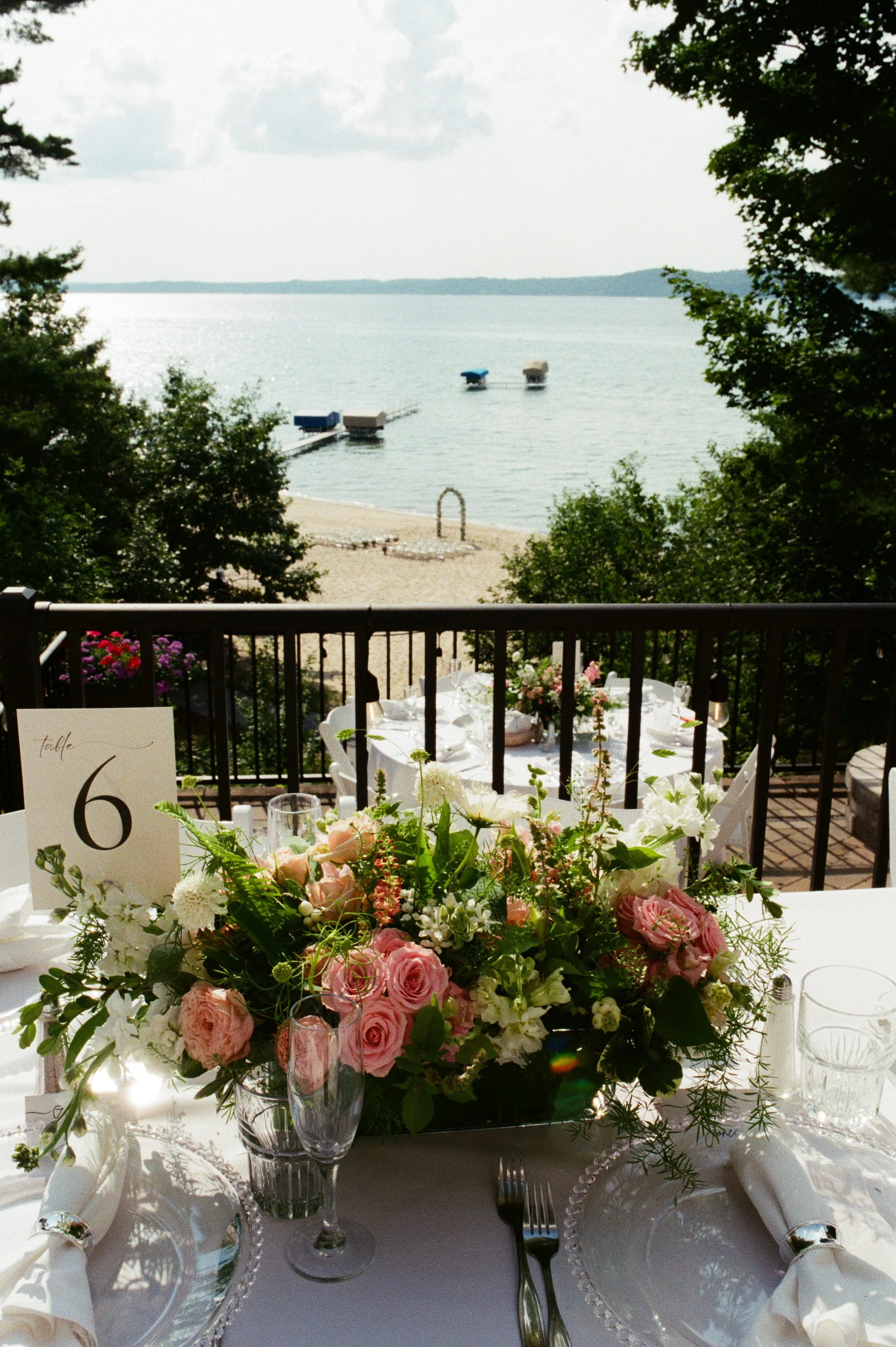 Colorful pink and white wedding centerpiece overlooking the lake and beach ceremony below.