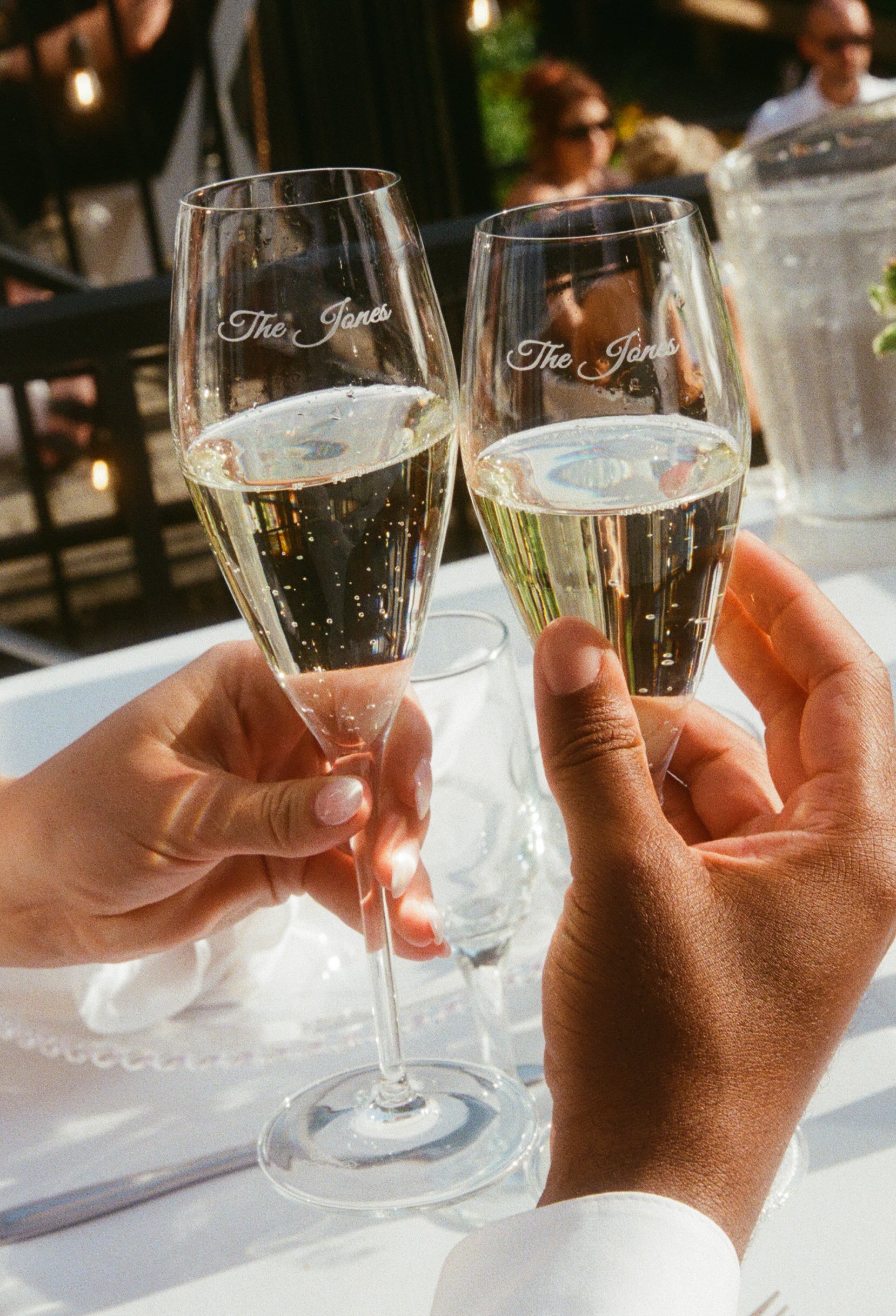 Bride and groom toasting with personalized champagne glasses during their lakeside wedding reception.