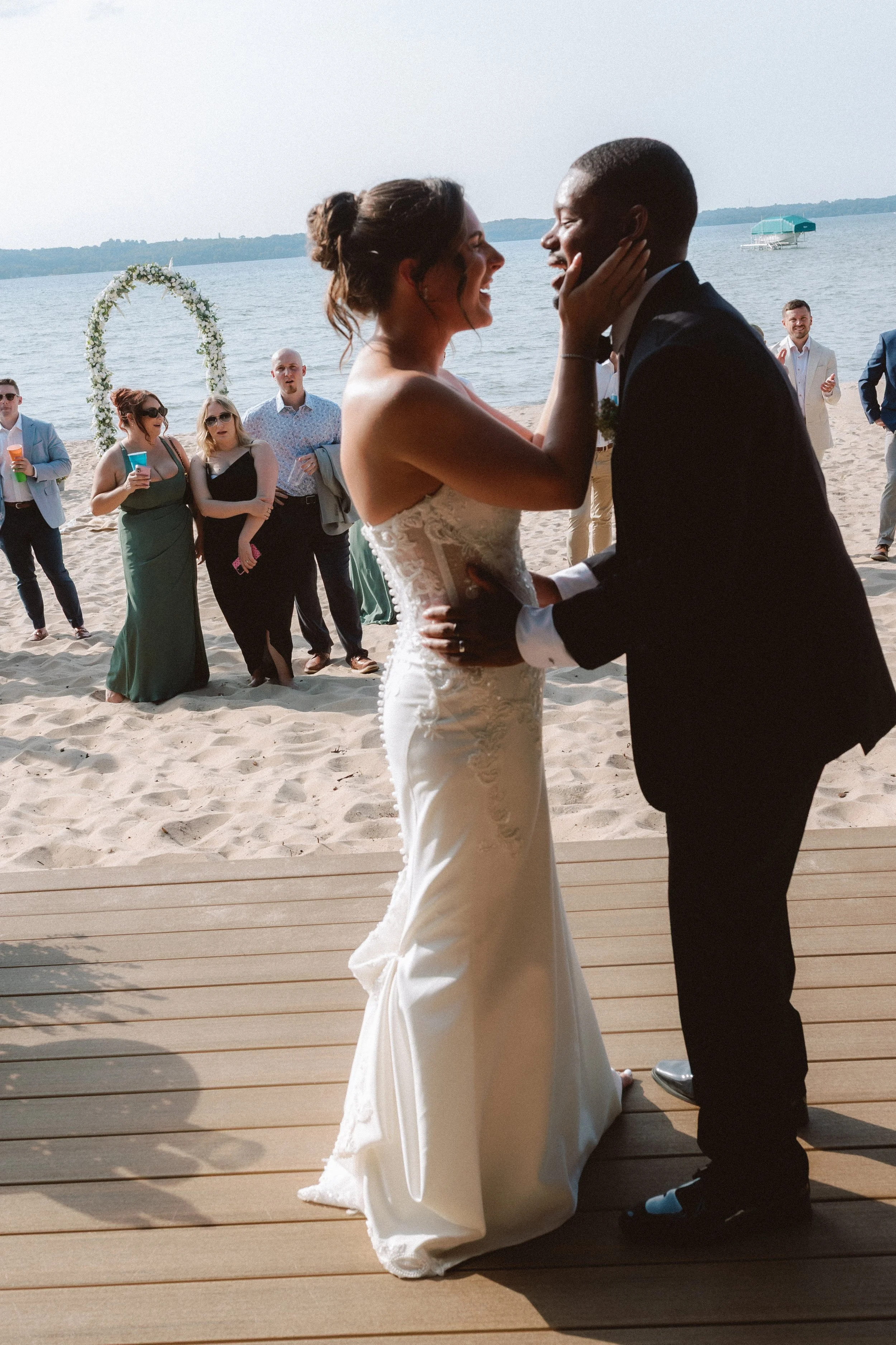 Newlyweds celebrating together with guests gathered behind them at their Northern Michigan backyard wedding.