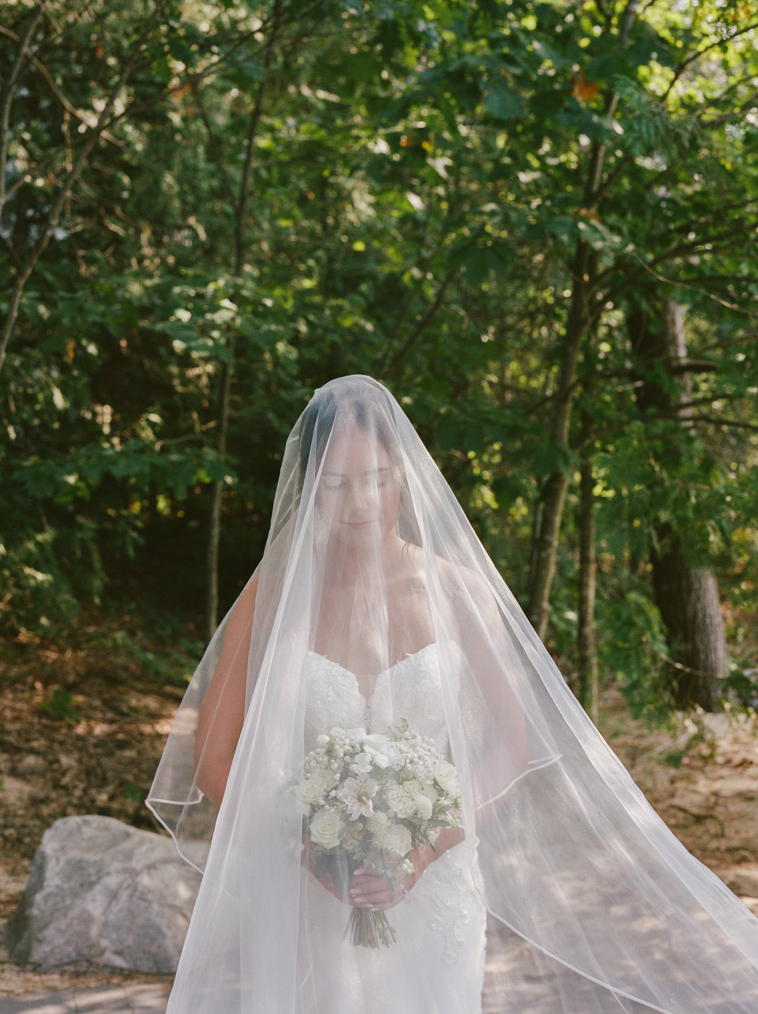 Bride holding her white bouquet beneath her veil during a Northern Michigan backyard wedding.
