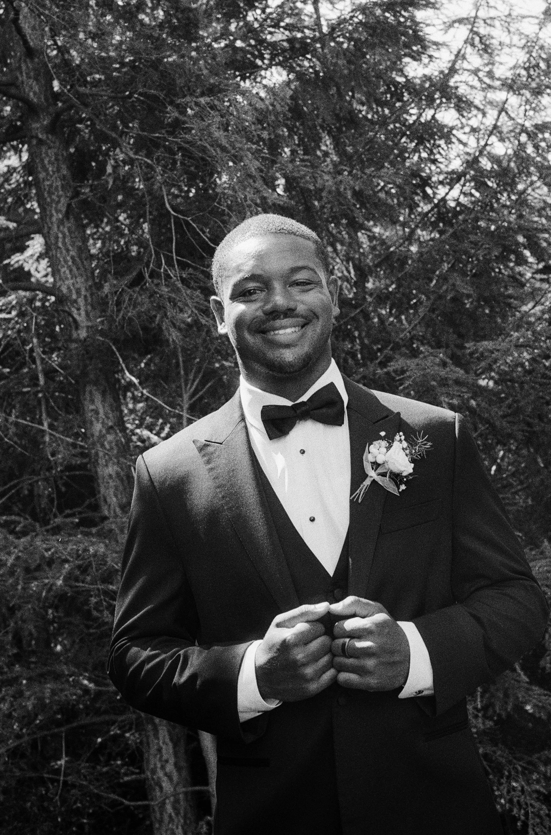 Black and white portrait of the smiling groom in his tuxedo during a Northern Michigan backyard wedding.