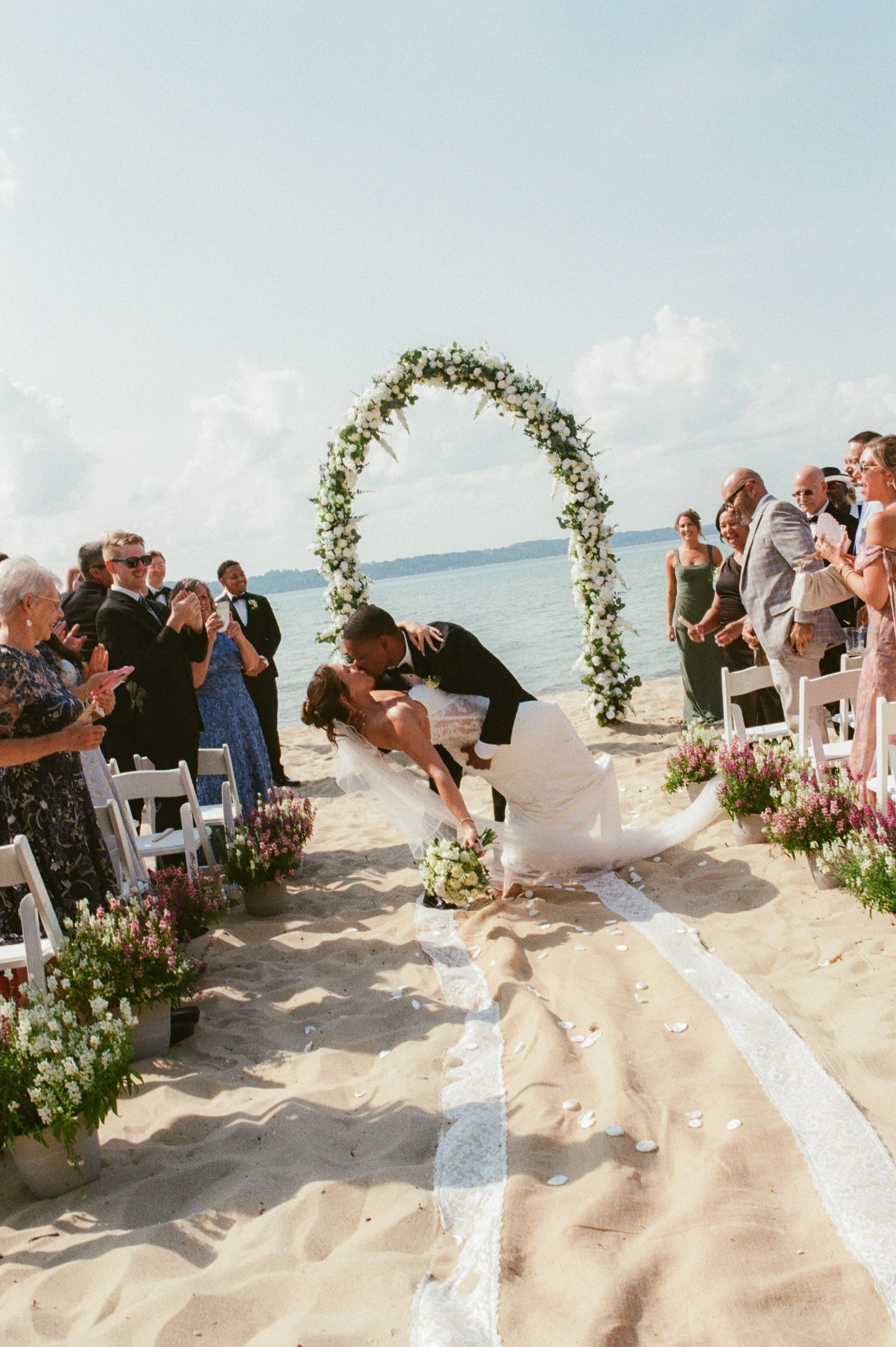 Bride and groom sharing a celebratory dip and kiss after their Northern Michigan backyard wedding ceremony.