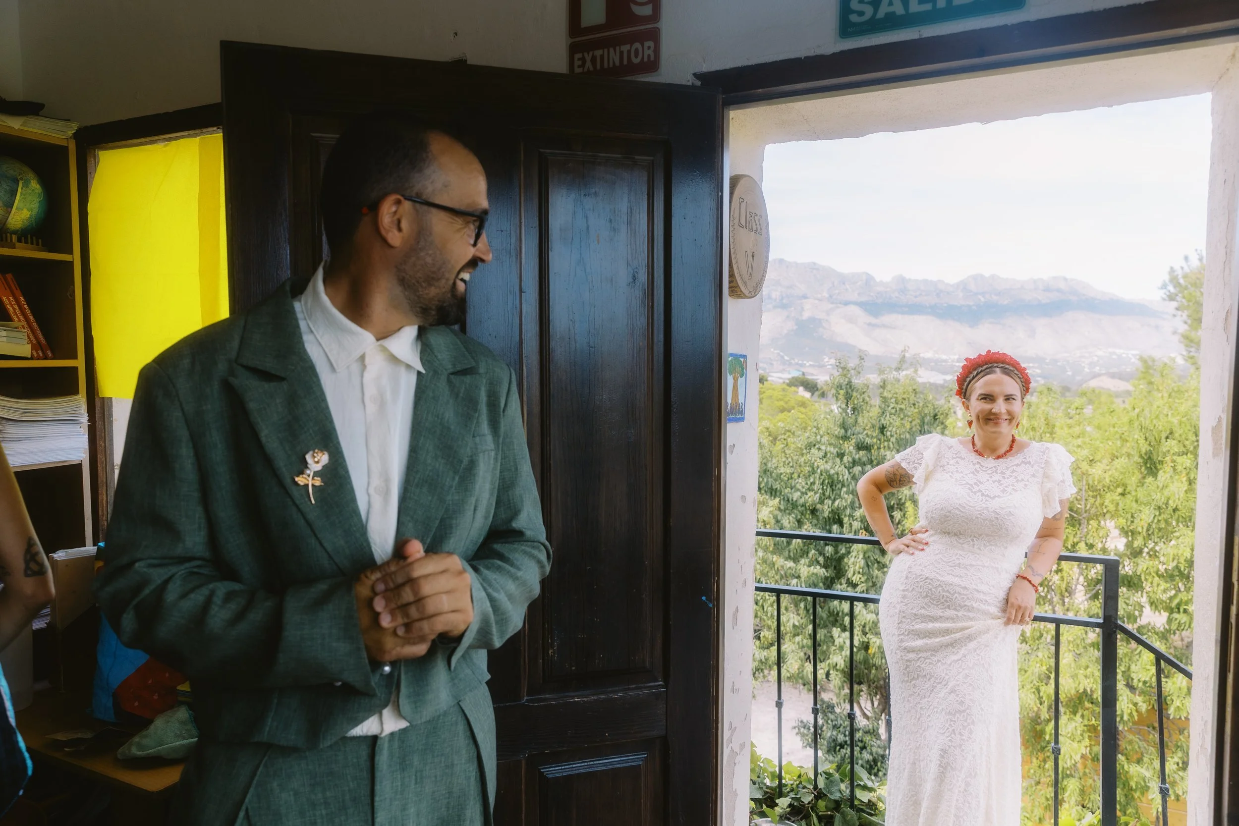Groom smiling at his partner on a balcony with mountain views during their Spain wedding.