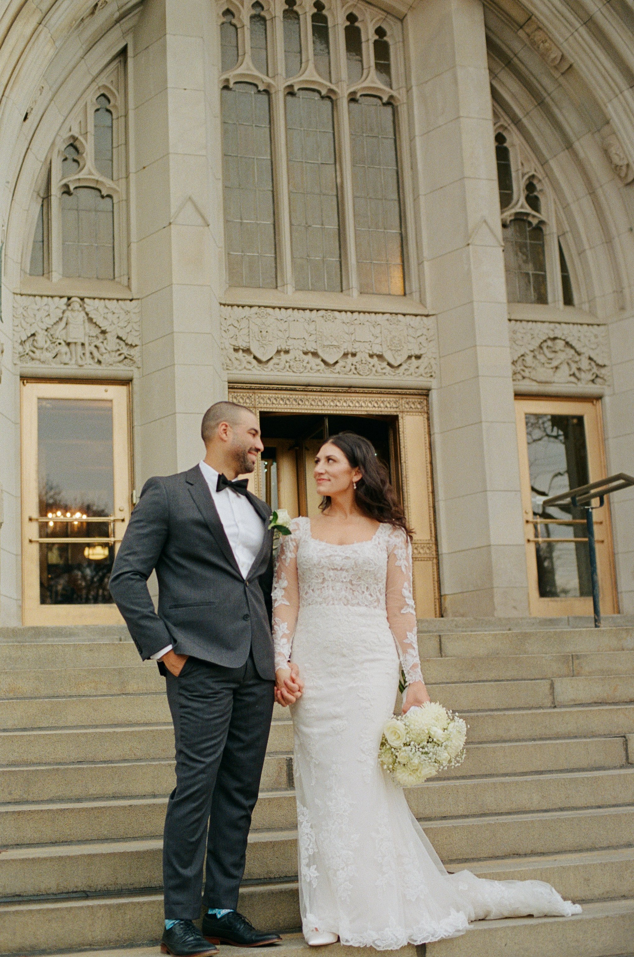 Bride and groom holding hands on the stone steps during their downtown Detroit wedding.