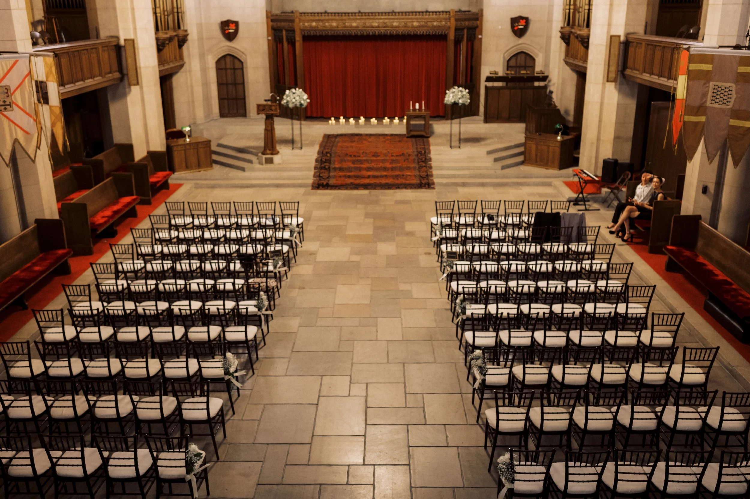 Wide view of the ceremony space set with black chairs, white florals, candles, and a central aisle for a downtown Detroit wedding.