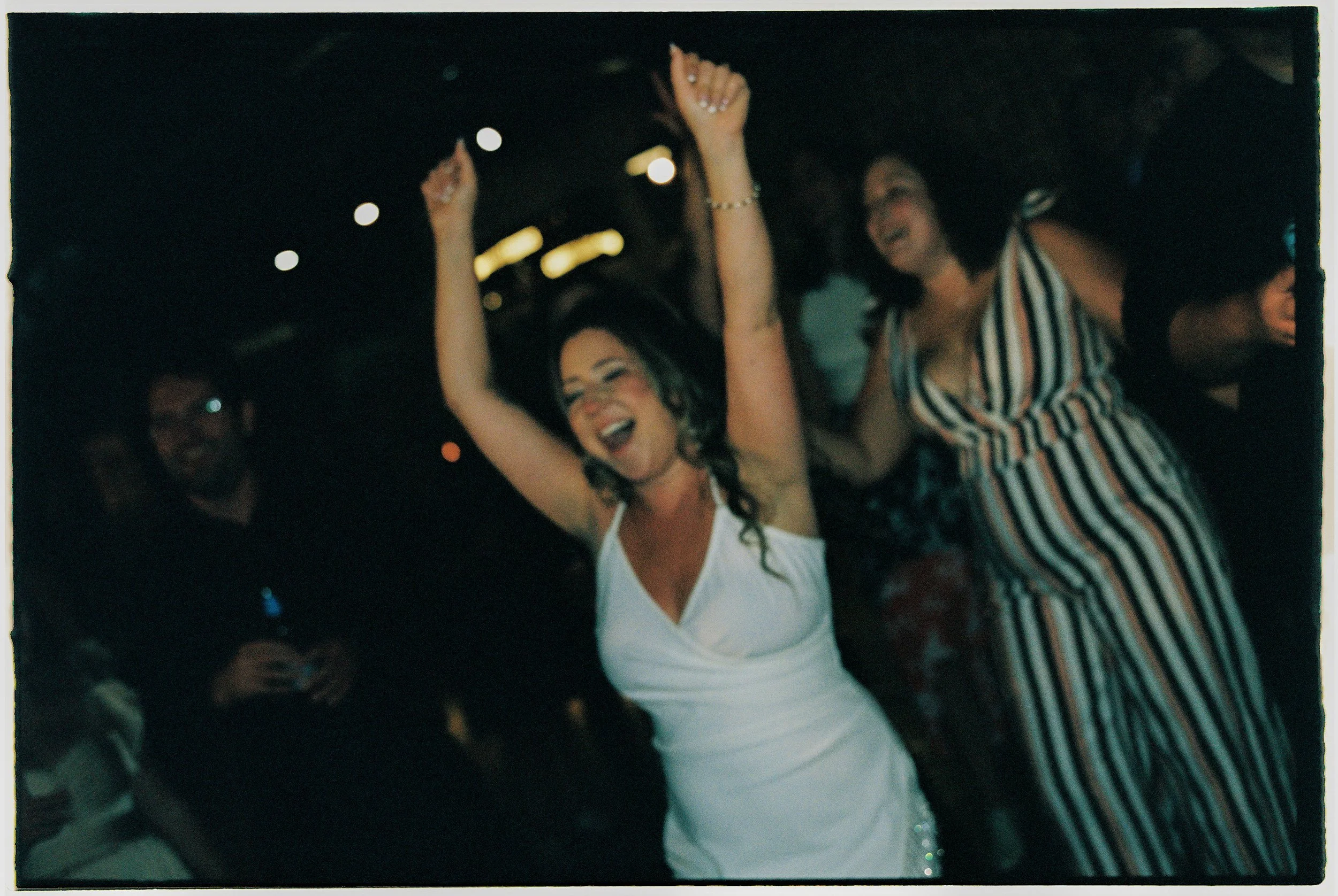 Bride dancing with arms raised, celebrating on the dance floor at Salvage One