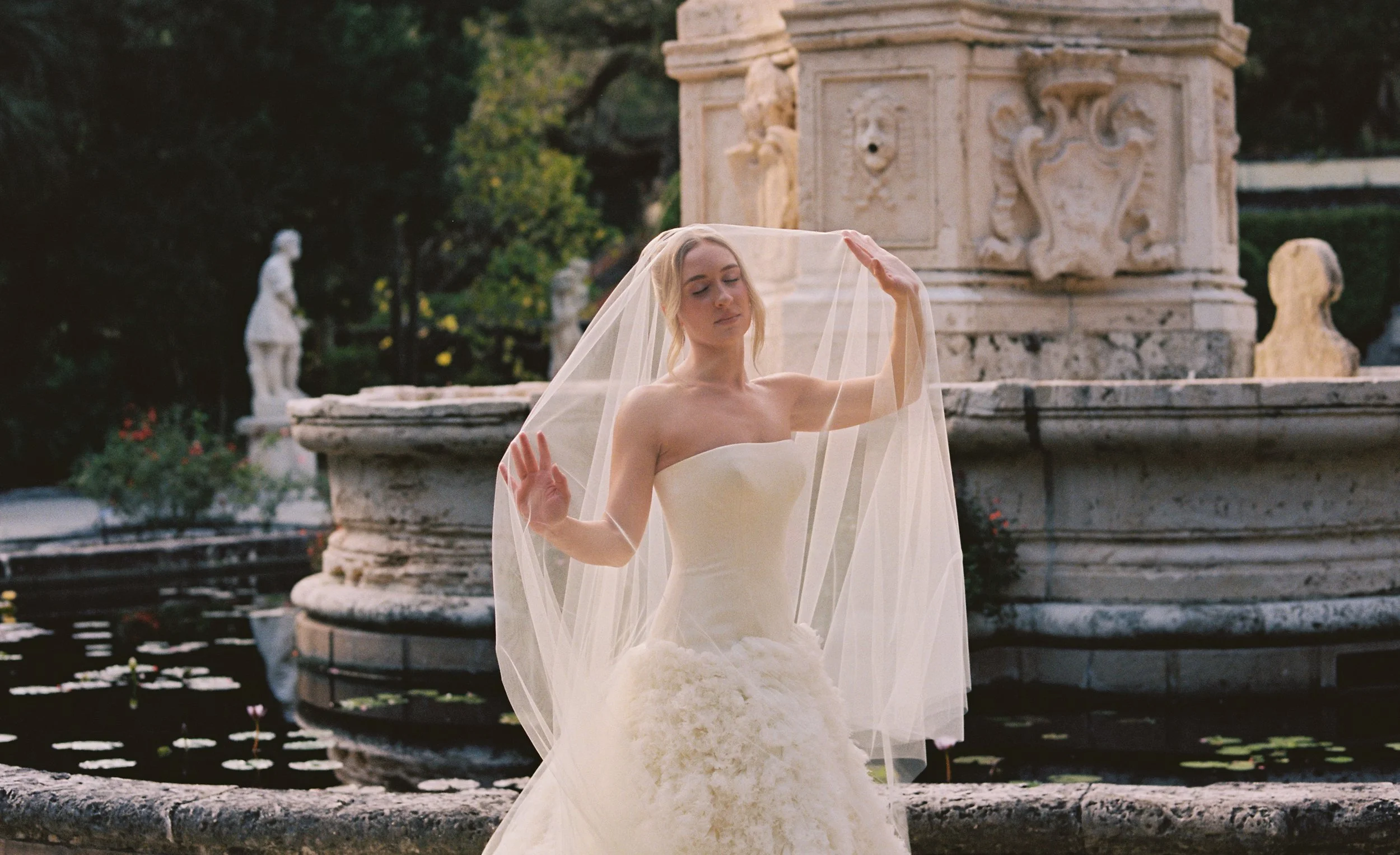 Bridal portrait beside the historic stone fountain and reflecting pool in the romantic gardens of Vizcaya Museum and Gardens.