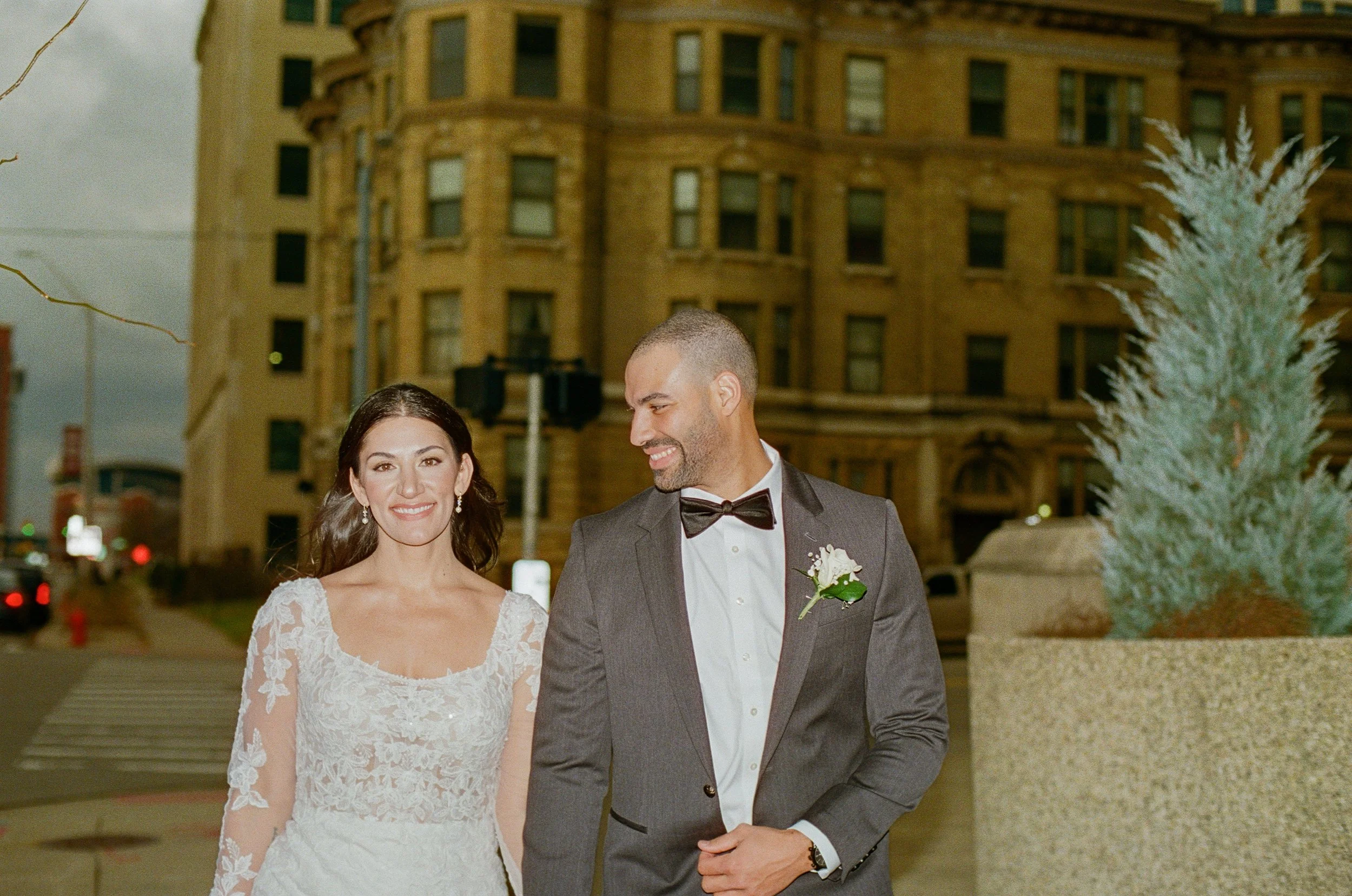 Bride and groom smiling together during wedding portraits outside in the city.