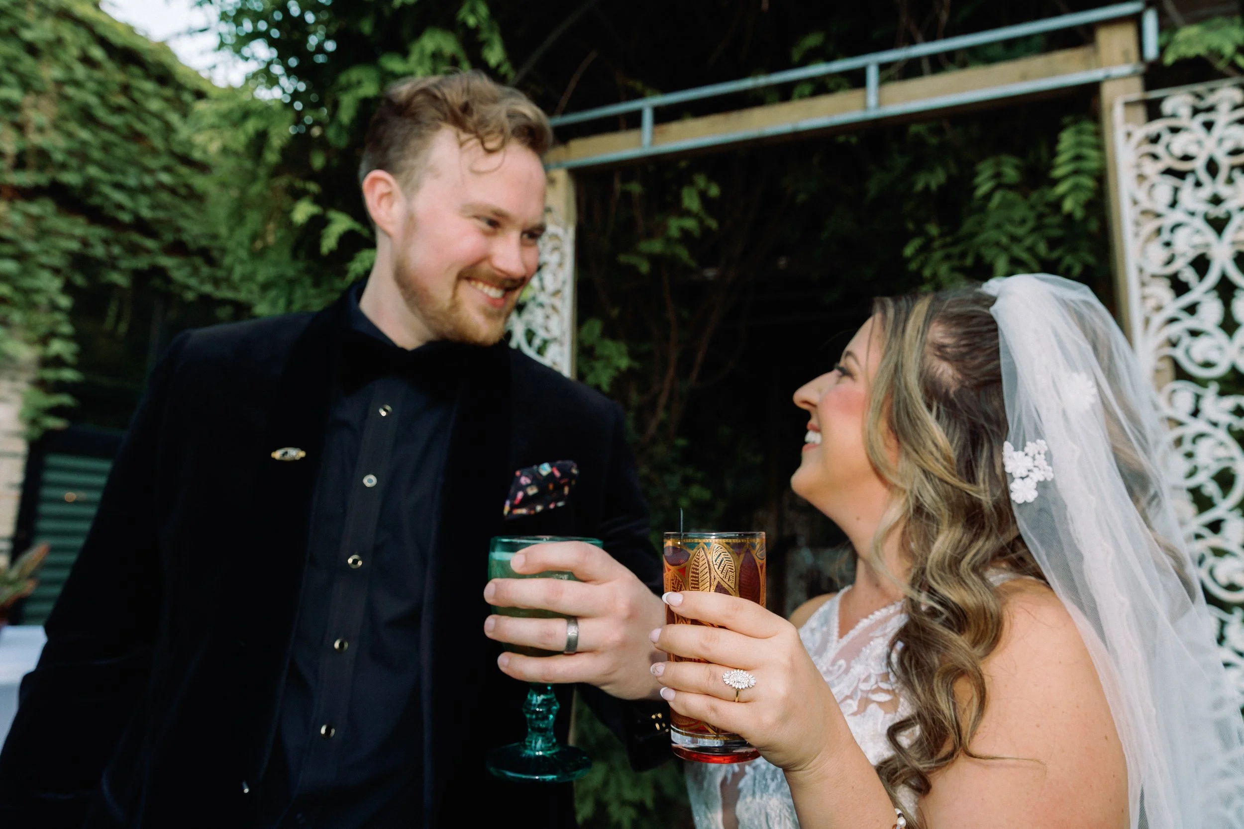 Newlyweds toasting drinks together outdoors in a lush garden setting