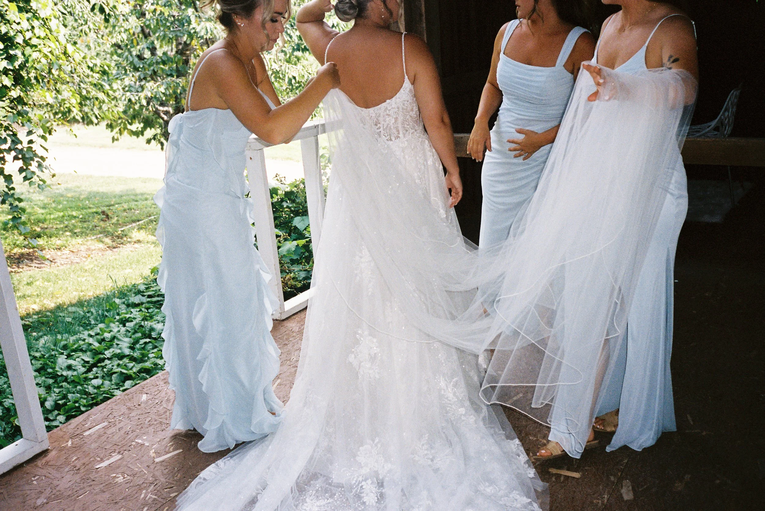 Bridesmaids helping the bride arrange her veil and wedding dress before the ceremony.