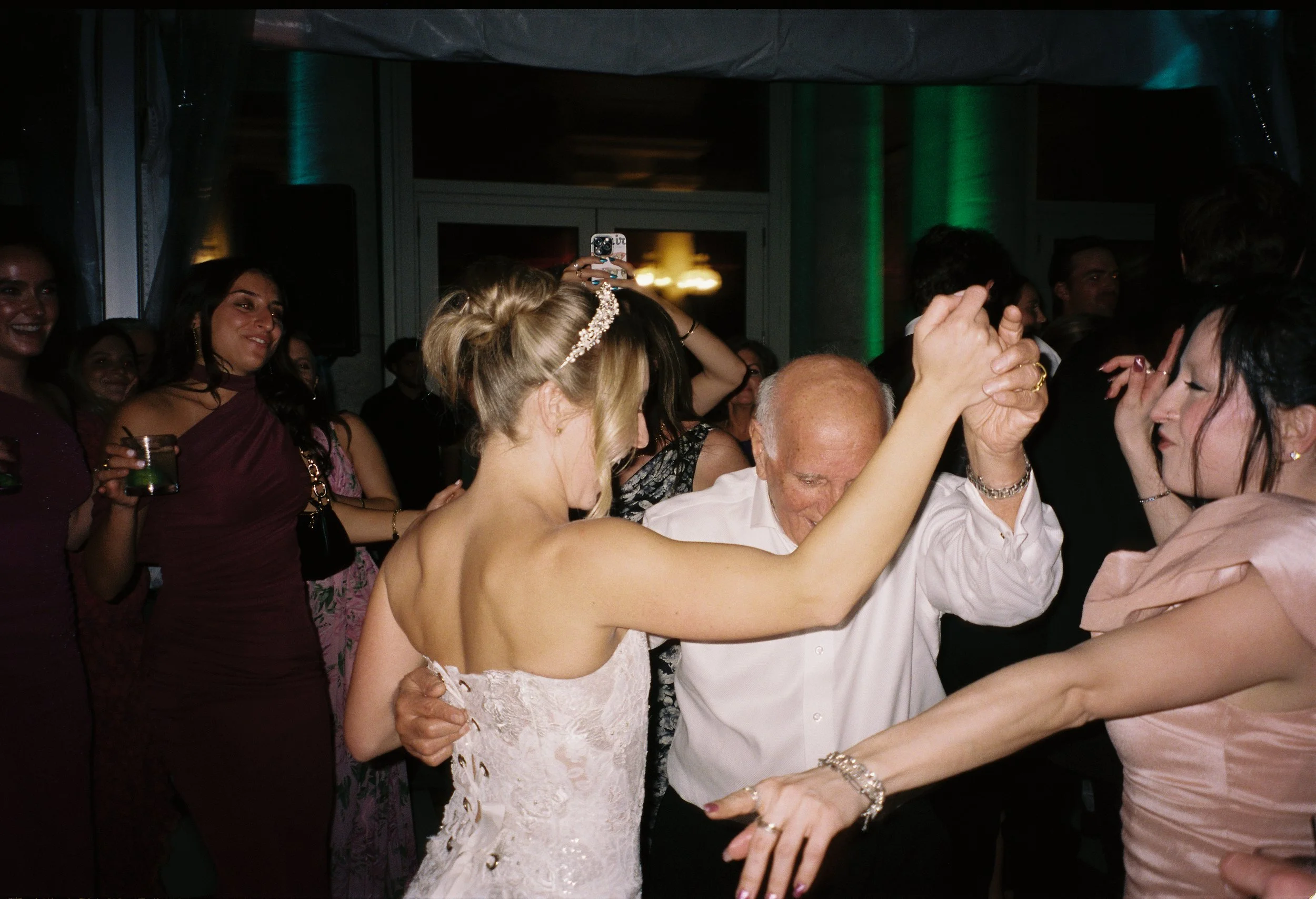 Bride dancing joyfully with family members on the reception dance floor.