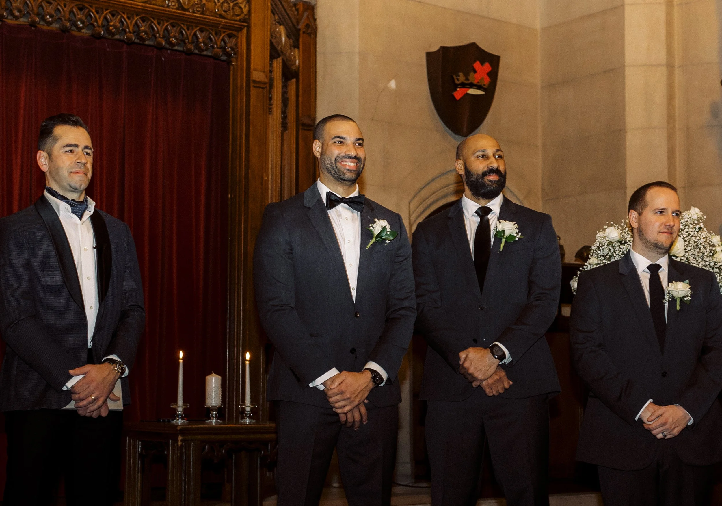 Groom smiling at the altar with his groomsmen while waiting for the bride.