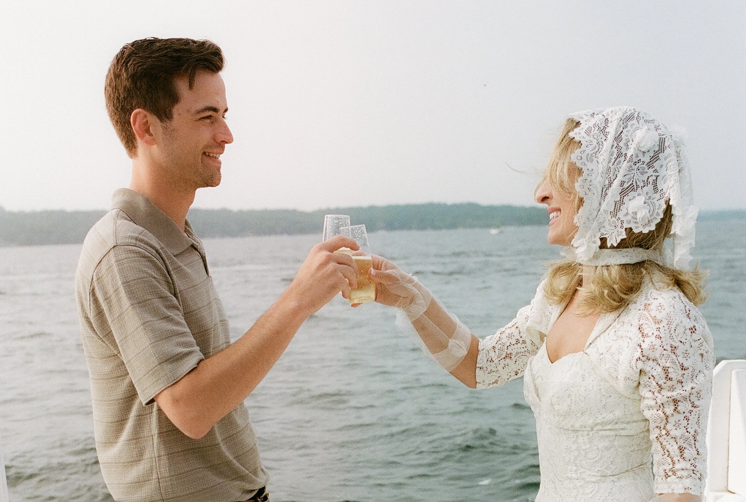Engaged couple toasting champagne aboard a vintage wooden boat during their Lake Geneva Engagement session at sunset.