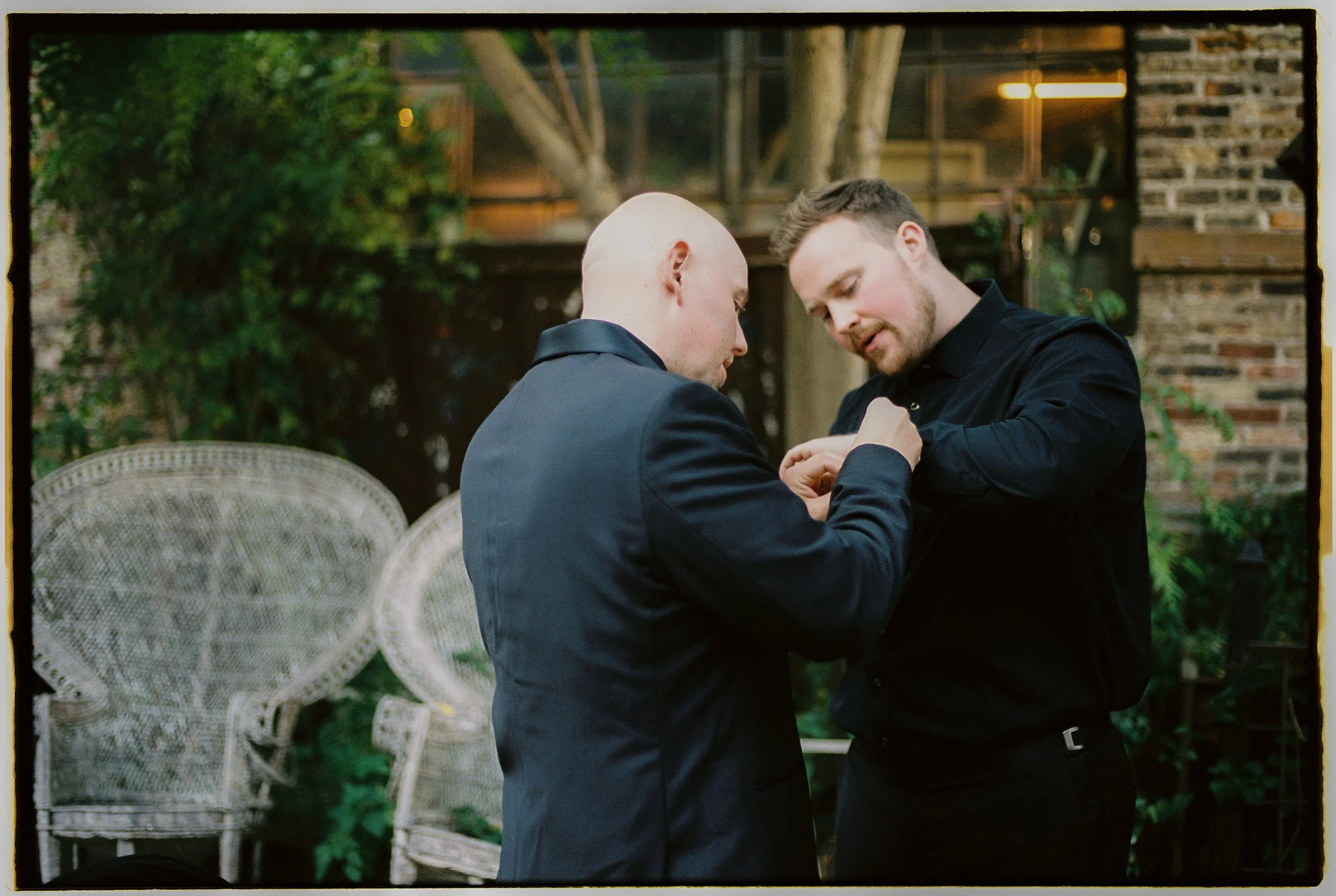 Groom adjusting cuff link with help from a groomsman outdoors before the ceremony