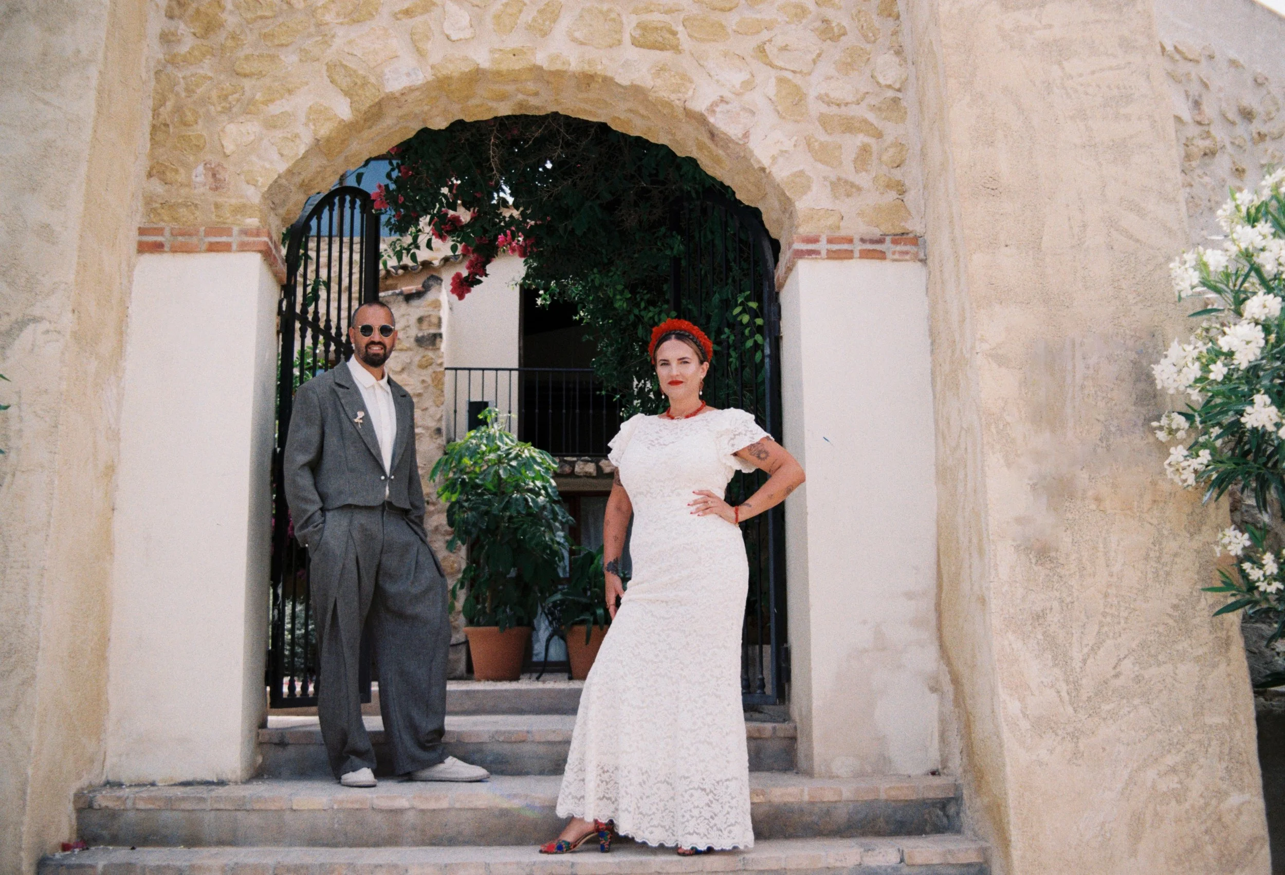 Bride and groom posing beneath a stone archway during their Spain wedding portraits.