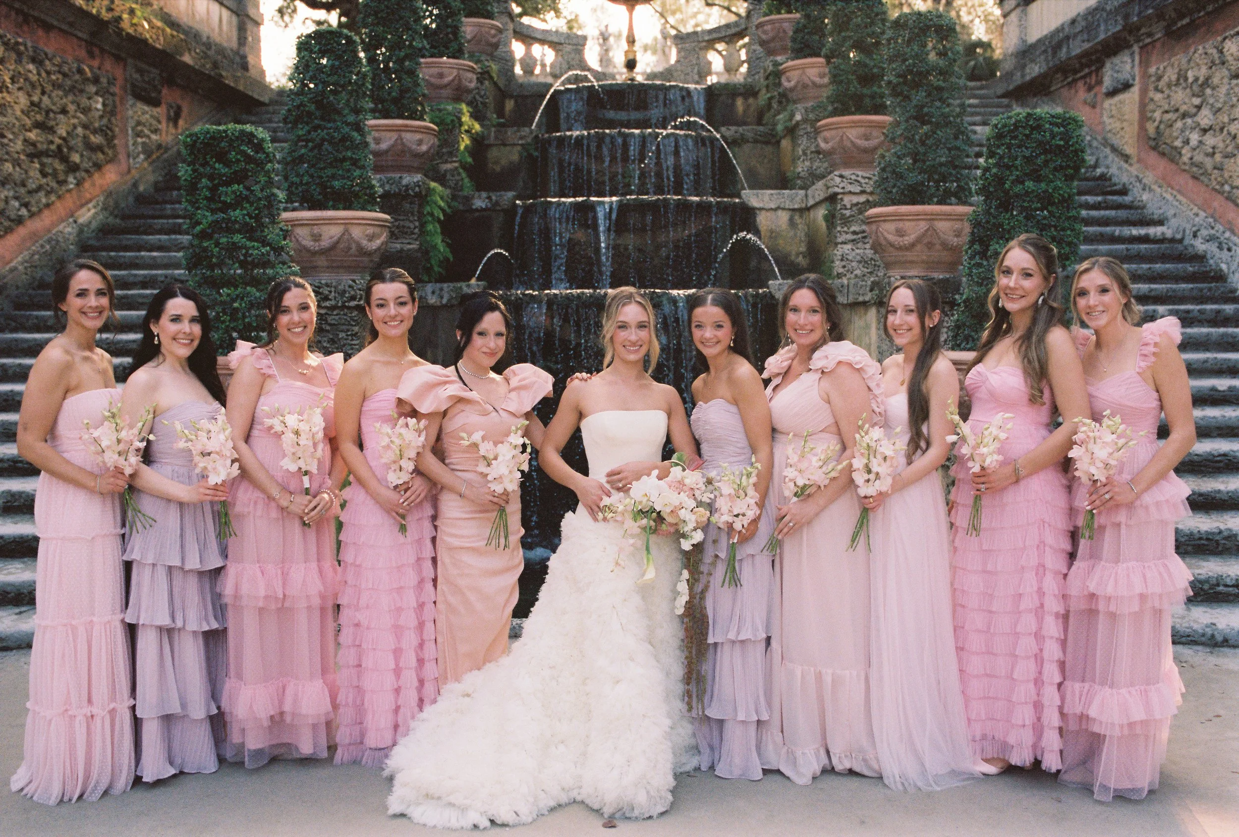 Bride standing with bridesmaids in blush and pink dresses in front of the grand fountain at their Vizcaya Museum and Gardens wedding.