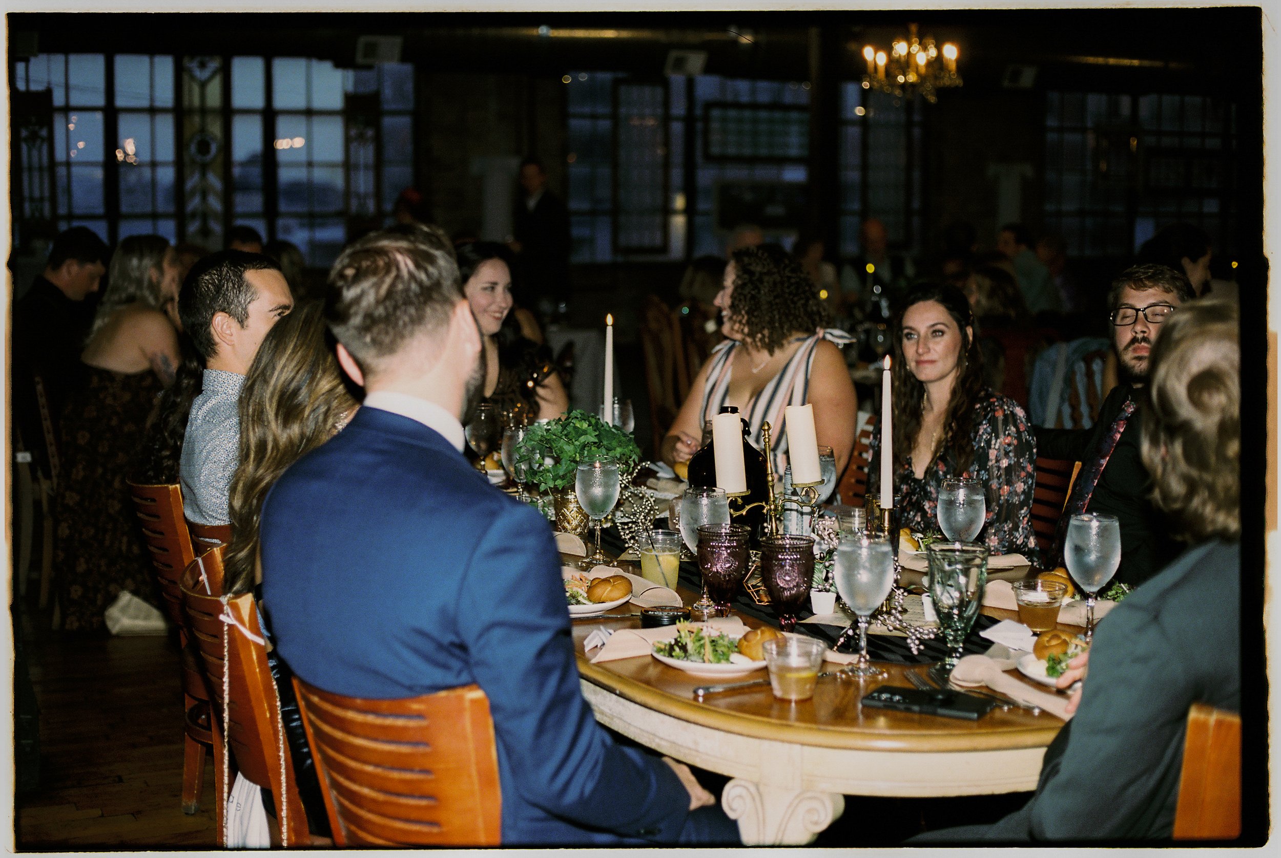 Guests seated around a candlelit reception table sharing a meal and conversation