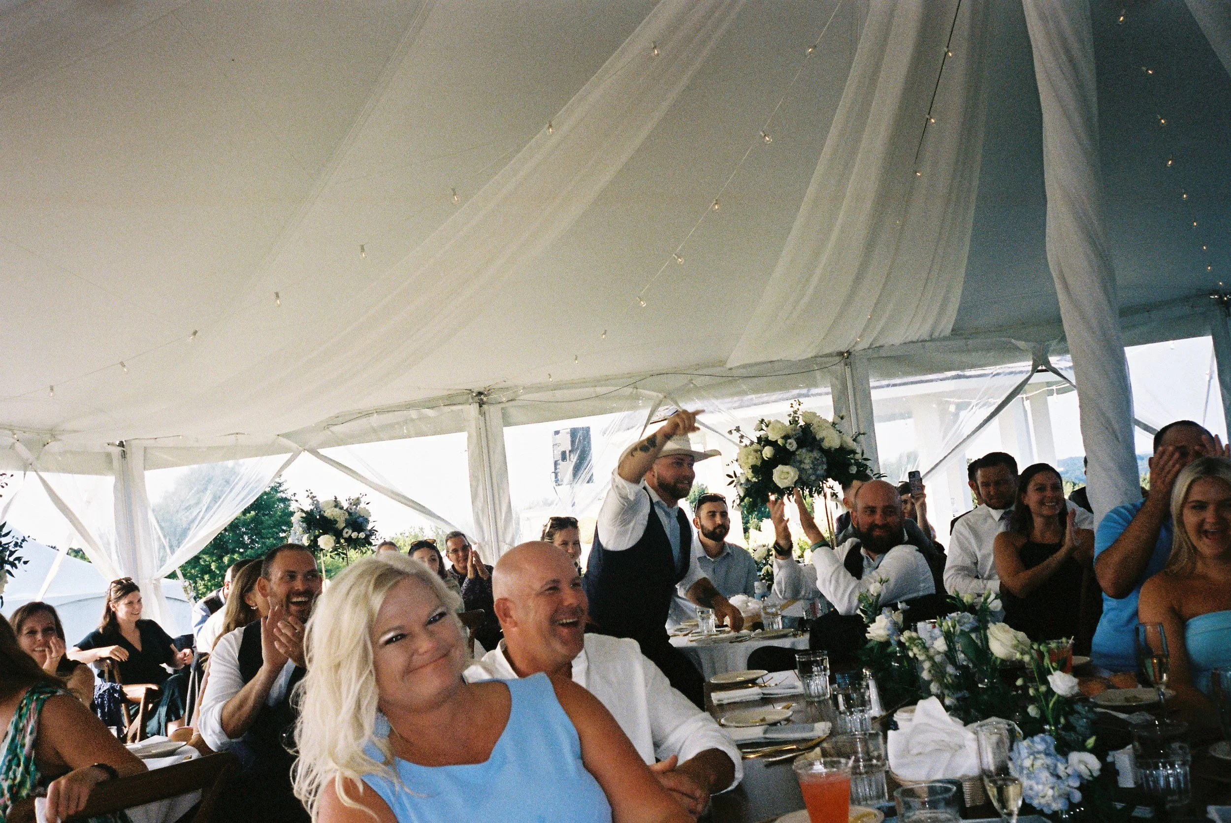 Wedding guests reacting during speeches inside a draped reception tent at a Northern Michigan vineyard wedding.