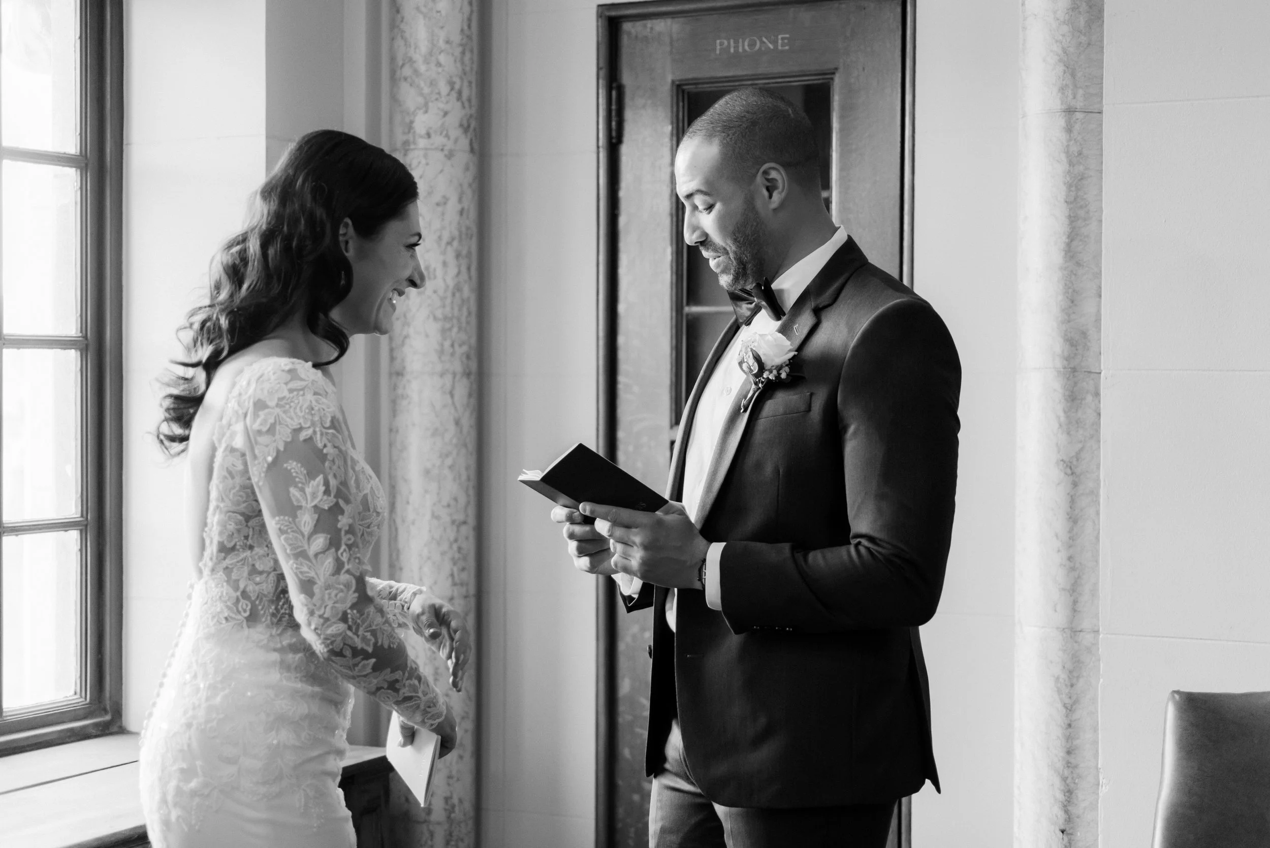 Black-and-white photo of the groom reading vows to the bride during a quiet moment together.