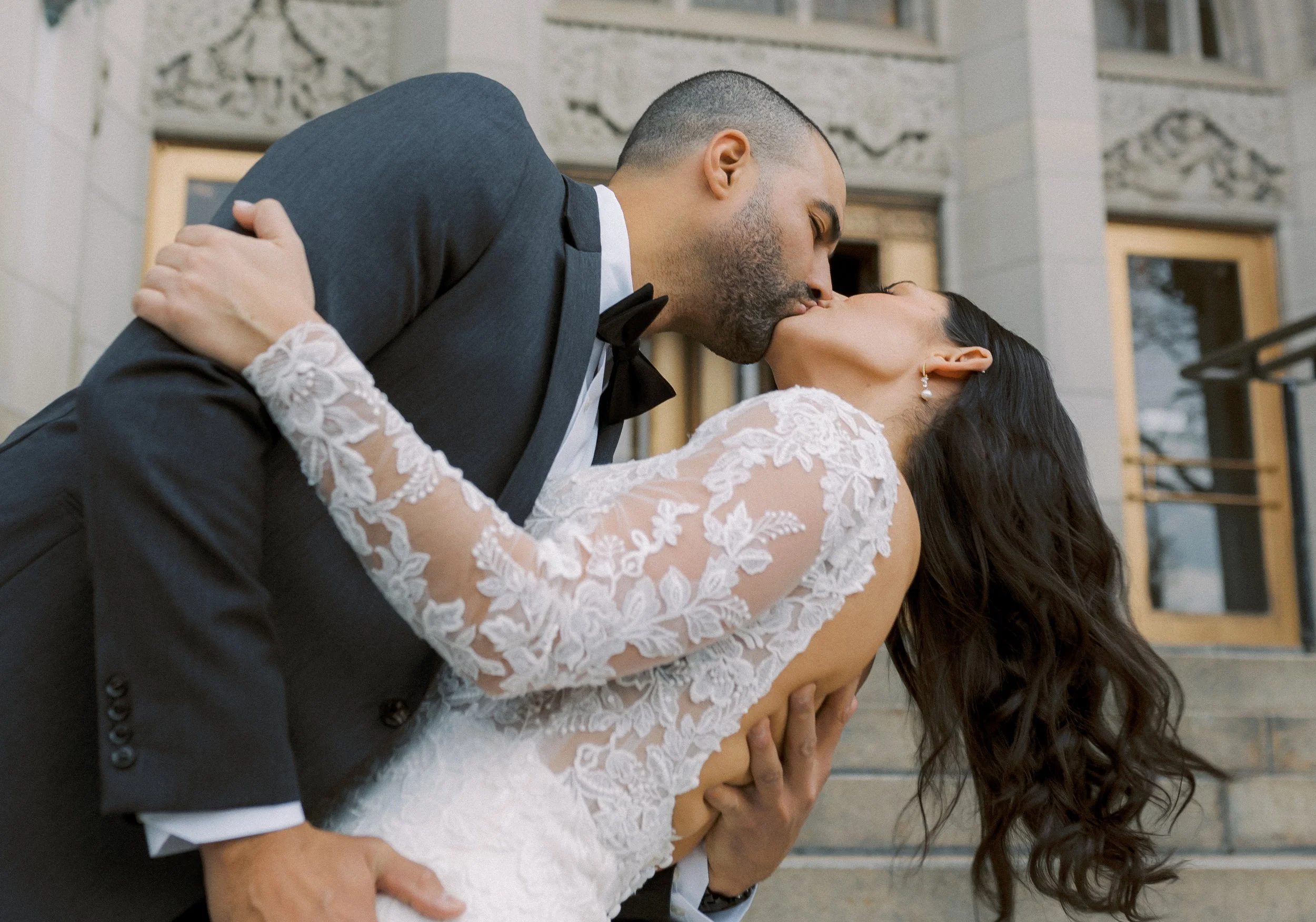A close up image of groom dipping his bride while kissing her