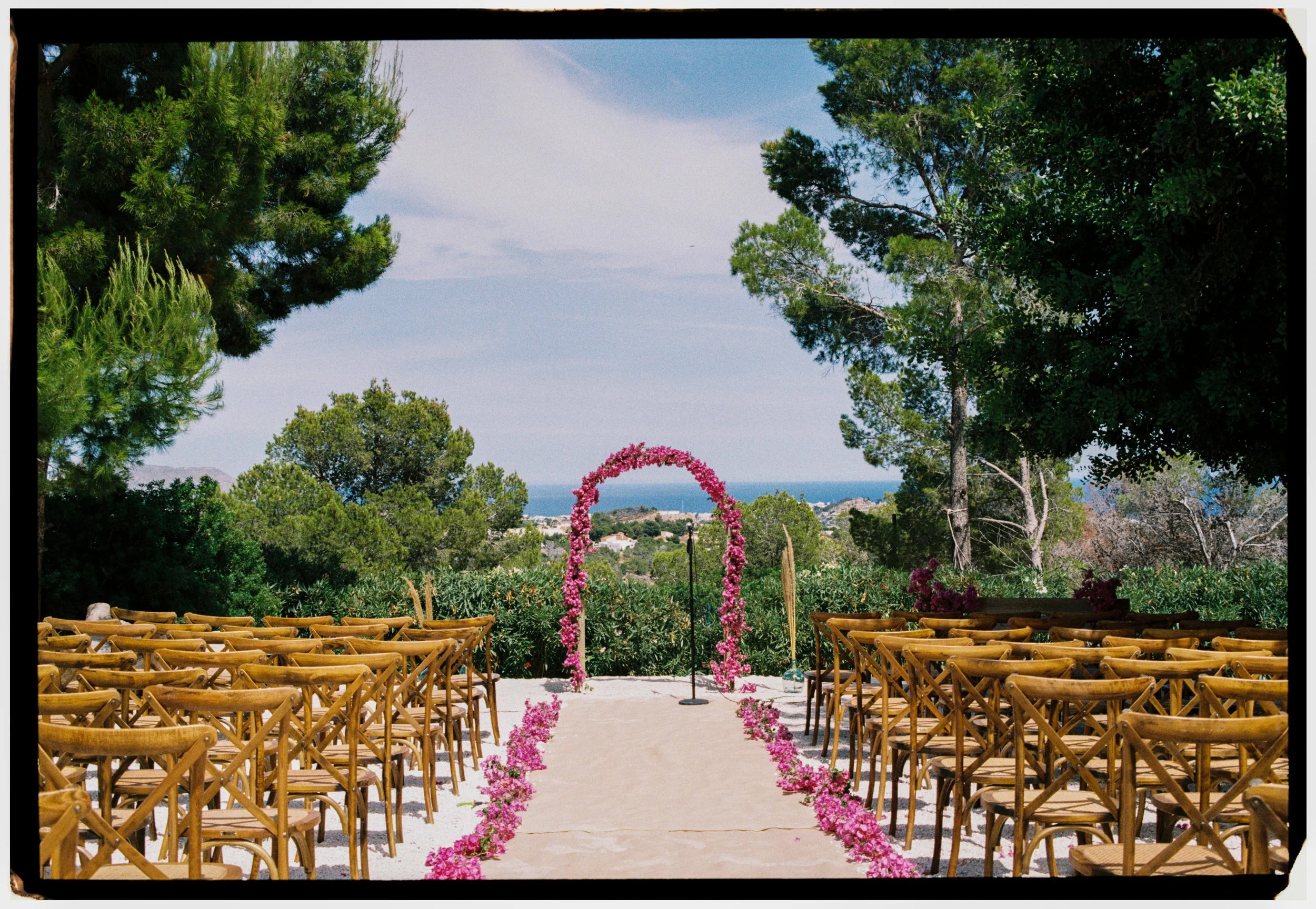 Outdoor ceremony space with a floral arch overlooking the Mediterranean coastline.