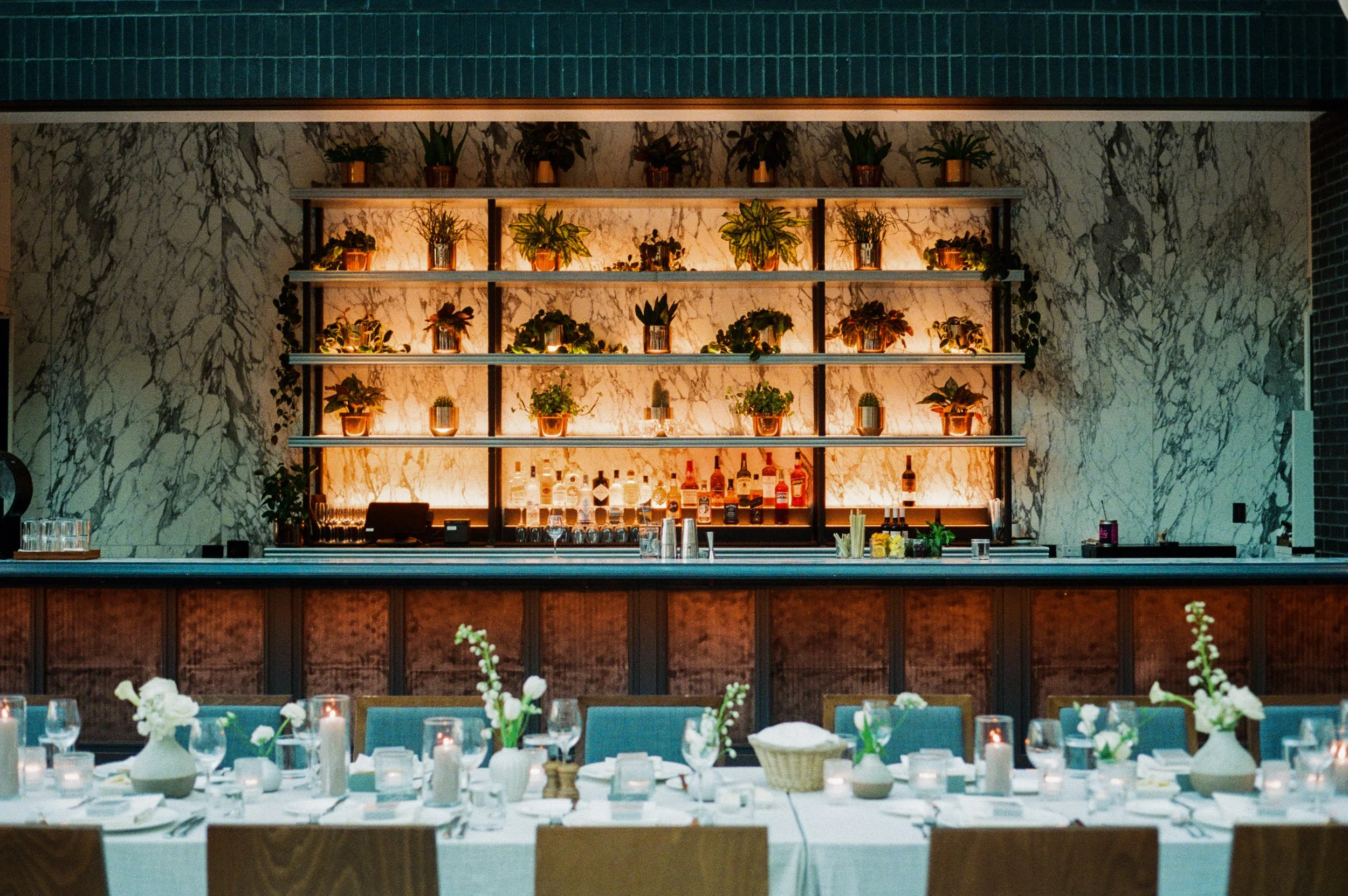 Reception bar with marble walls, glowing shelves, and candlelit wedding details at Shinola Hotel