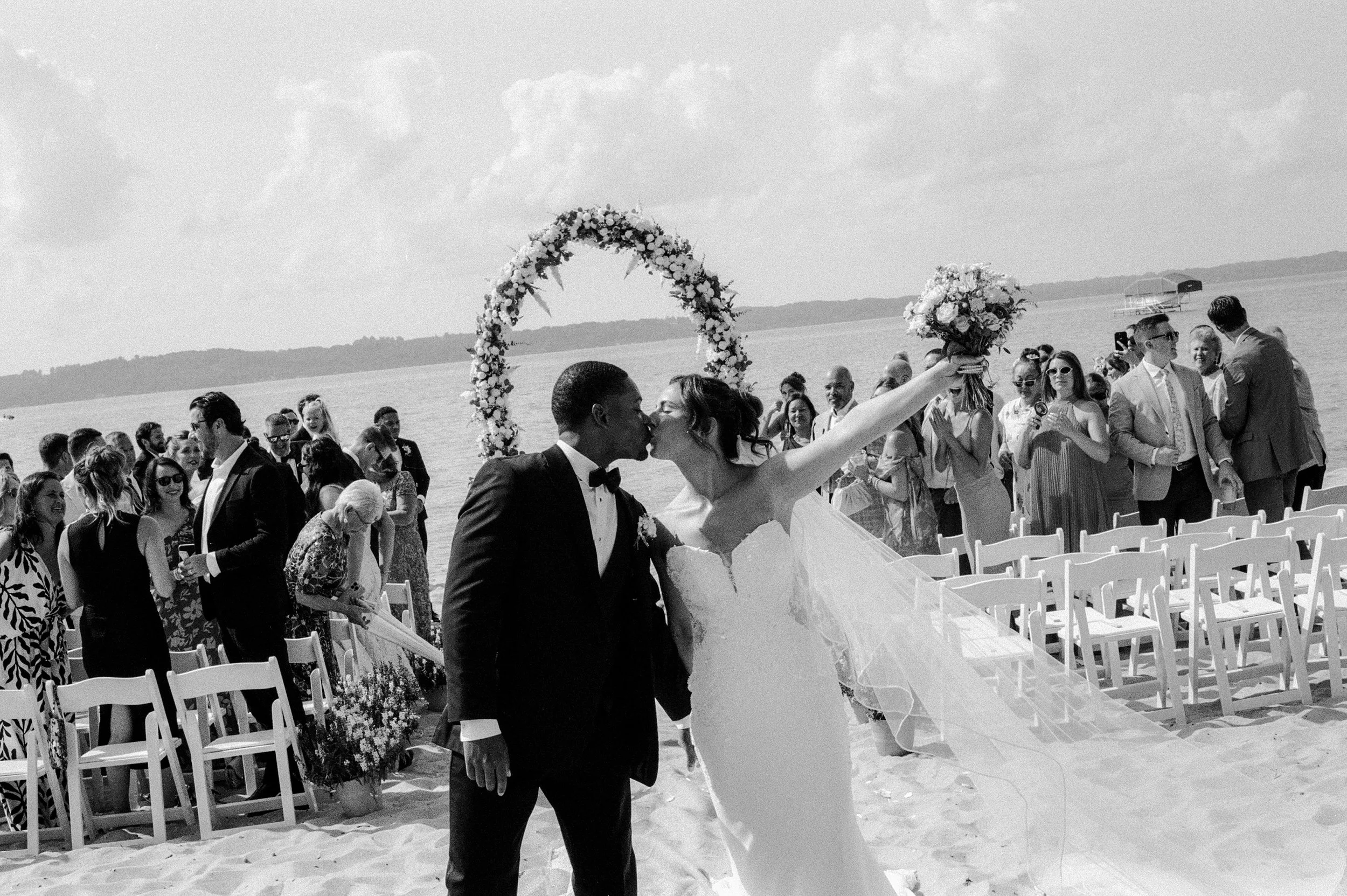 Black and white photo of the newlyweds kissing after their Northern Michigan backyard wedding ceremony.