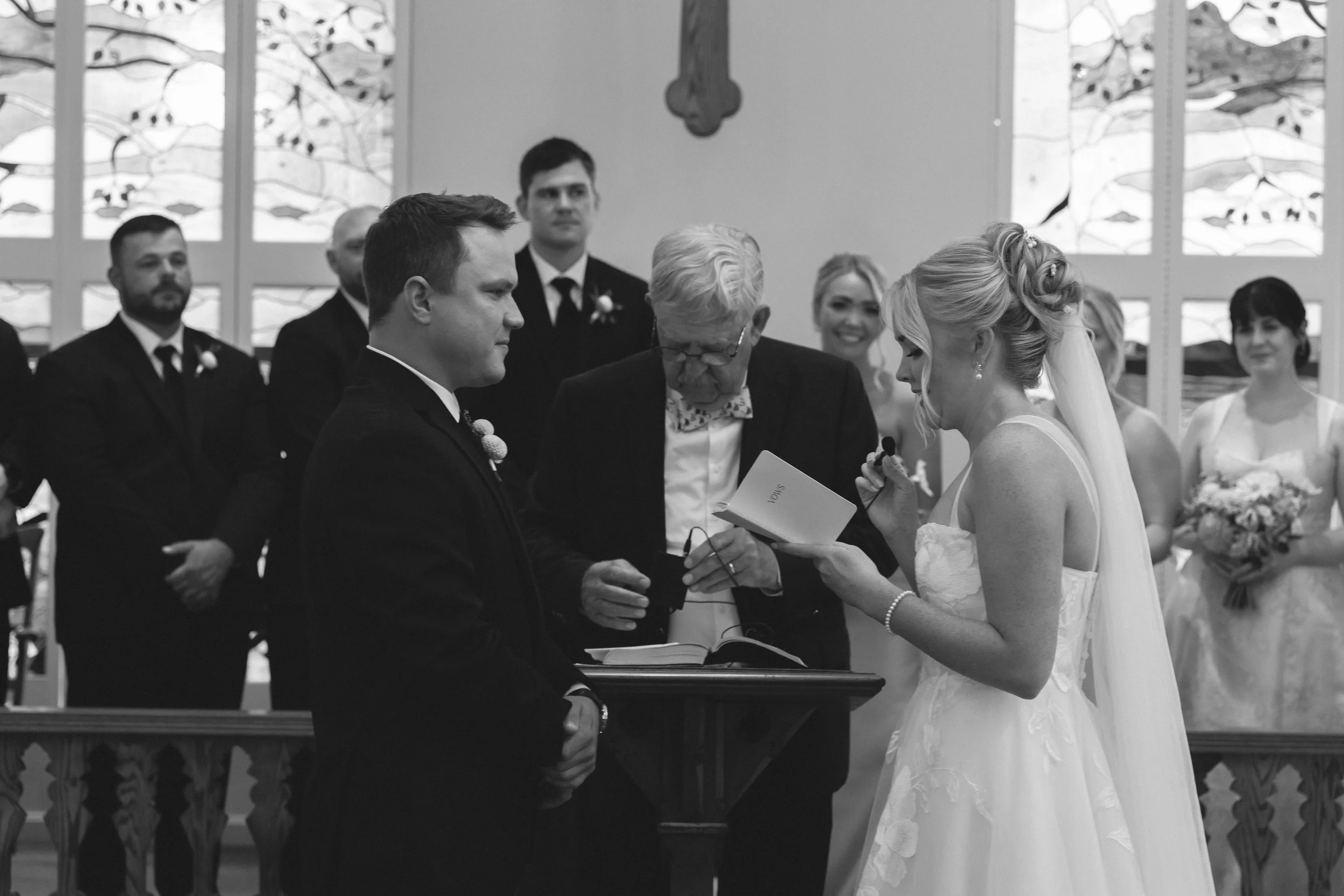 Black and white photo of a bride reading her vows during an intimate wedding ceremony at Stafford's Perry Hotel.