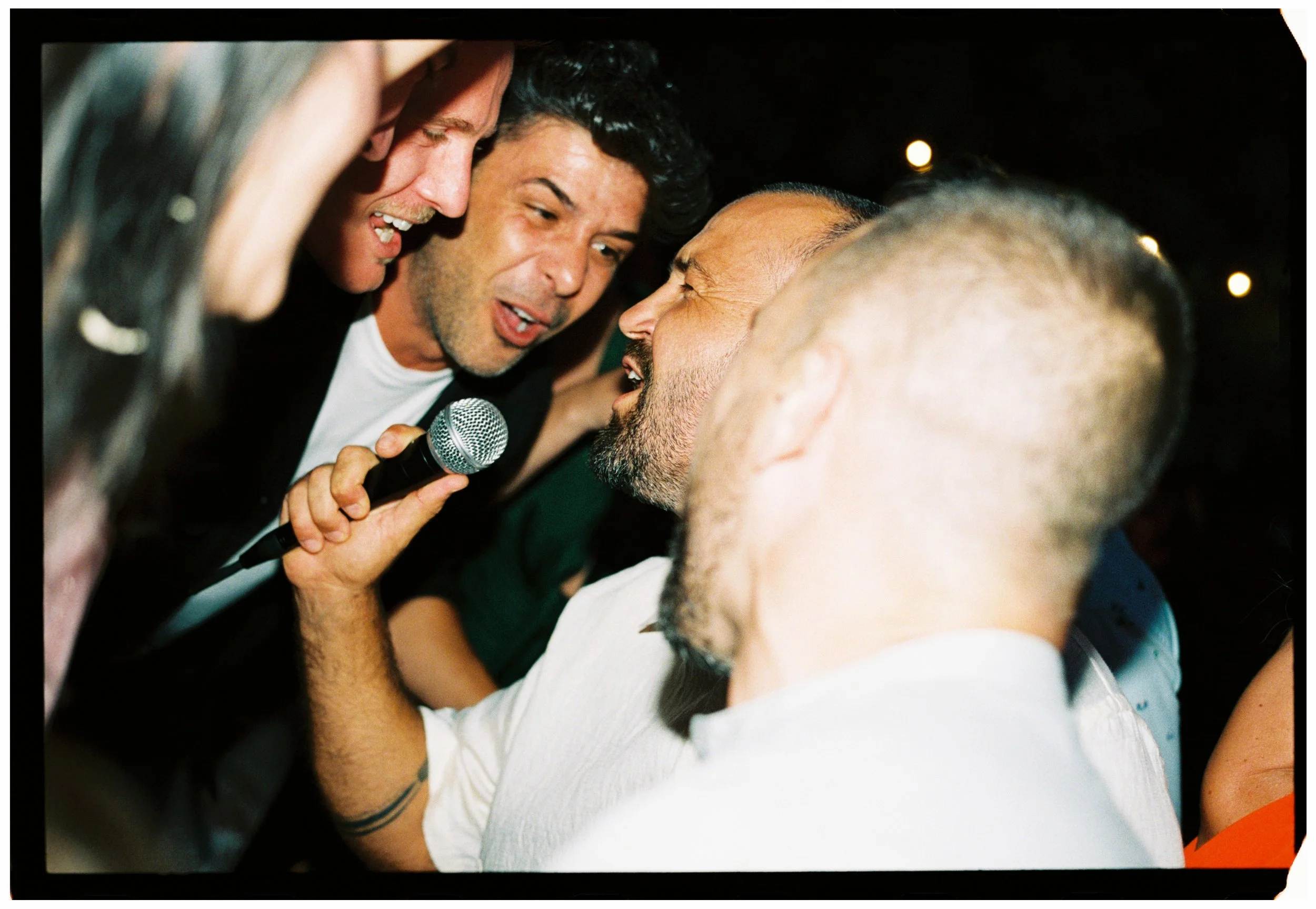 Groom singing into a microphone with friends during the wedding reception party.