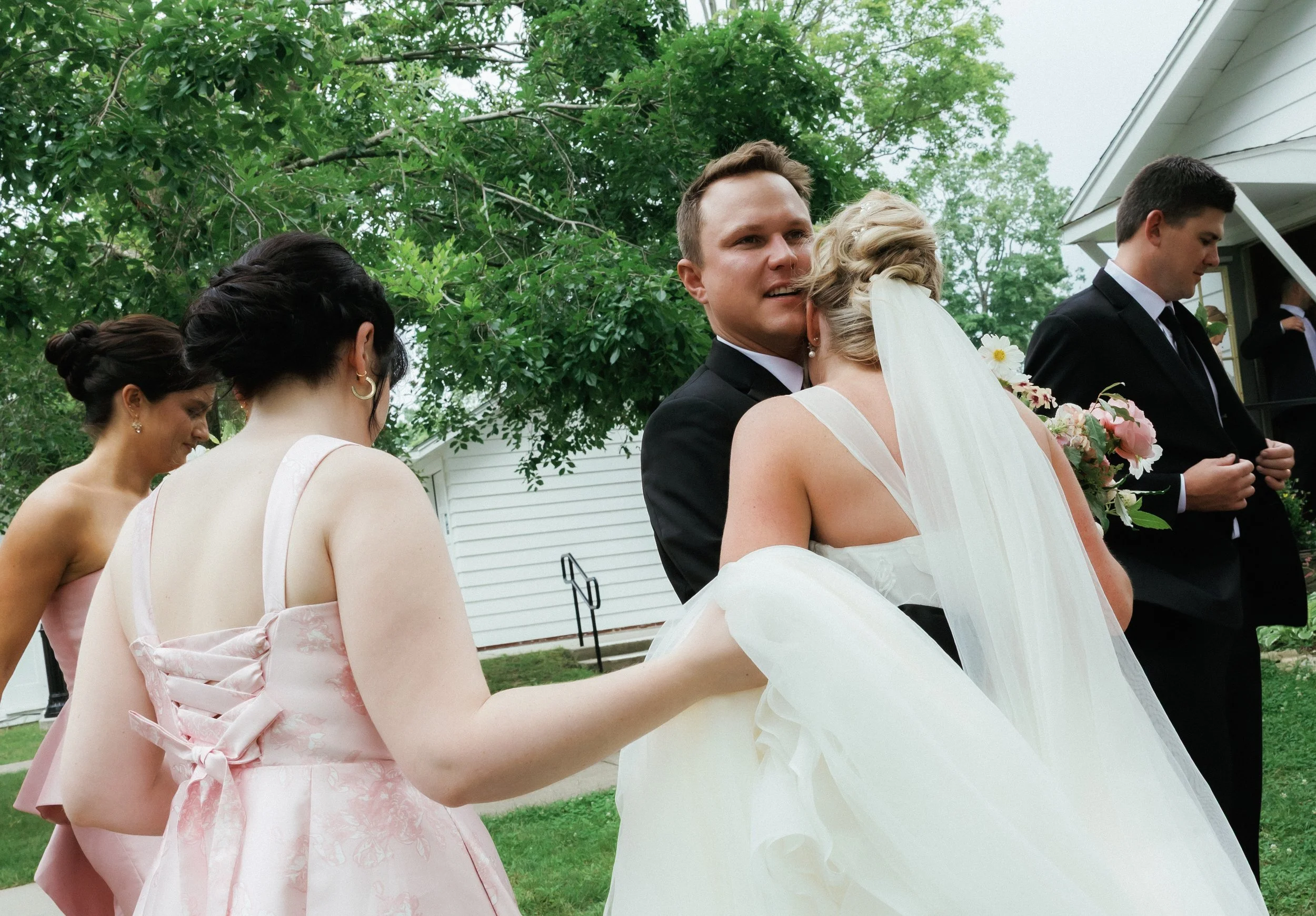 Bride sharing a quiet embrace with a family member or bridesmaid outdoors after the ceremony.