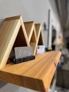 Close-up of a wooden shelf with small chalkboard signs and decorative wooden A-frames in a row.