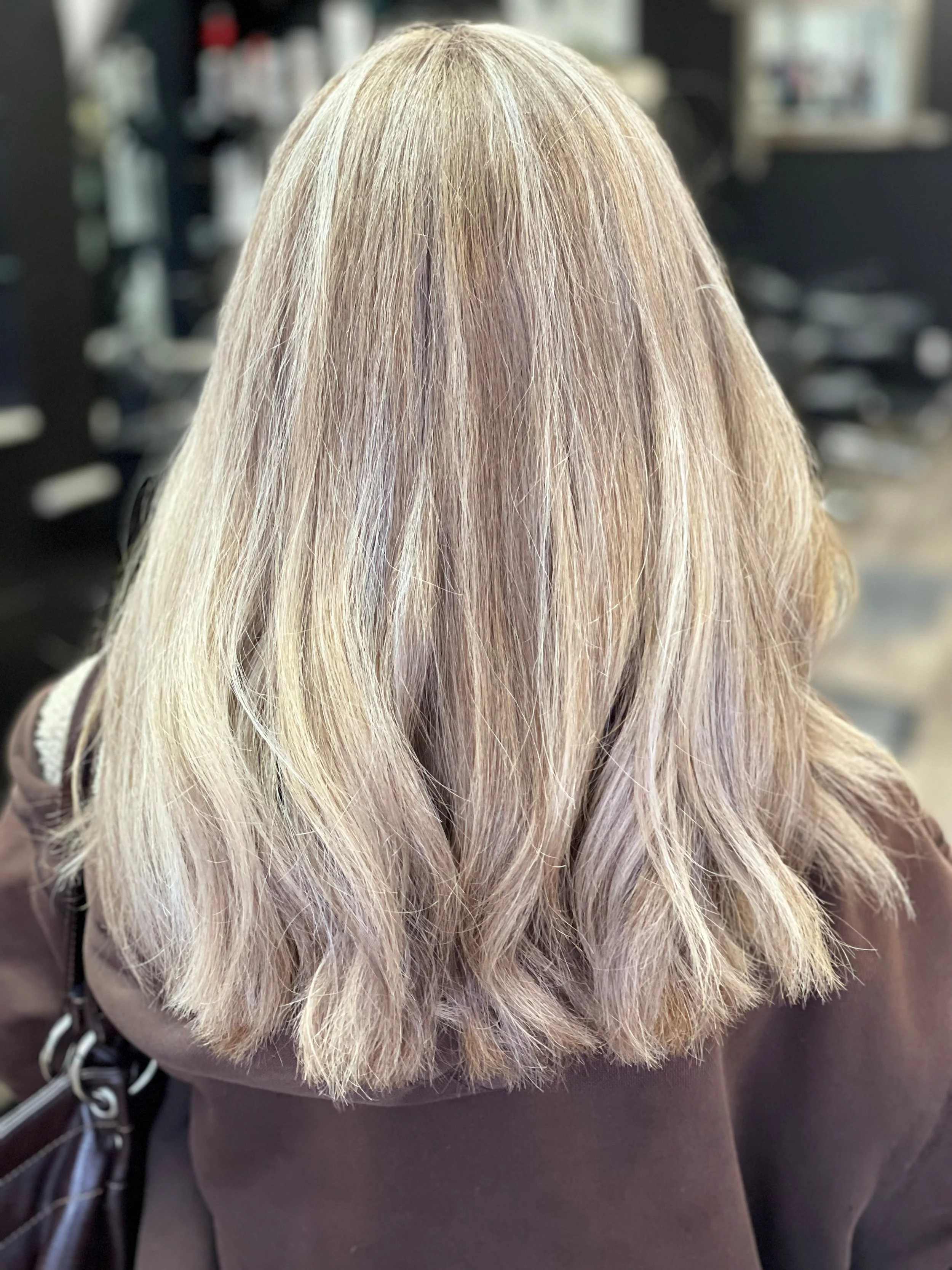 Back view of a woman's shoulder-length blonde hair, highlighting light blonde and darker blonde shades, with a slightly wavy texture.