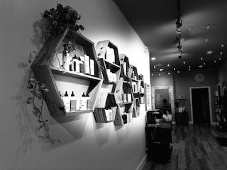 Interior view of a room with shelves on the wall holding various items, and a doorway leading to another room in the background.
